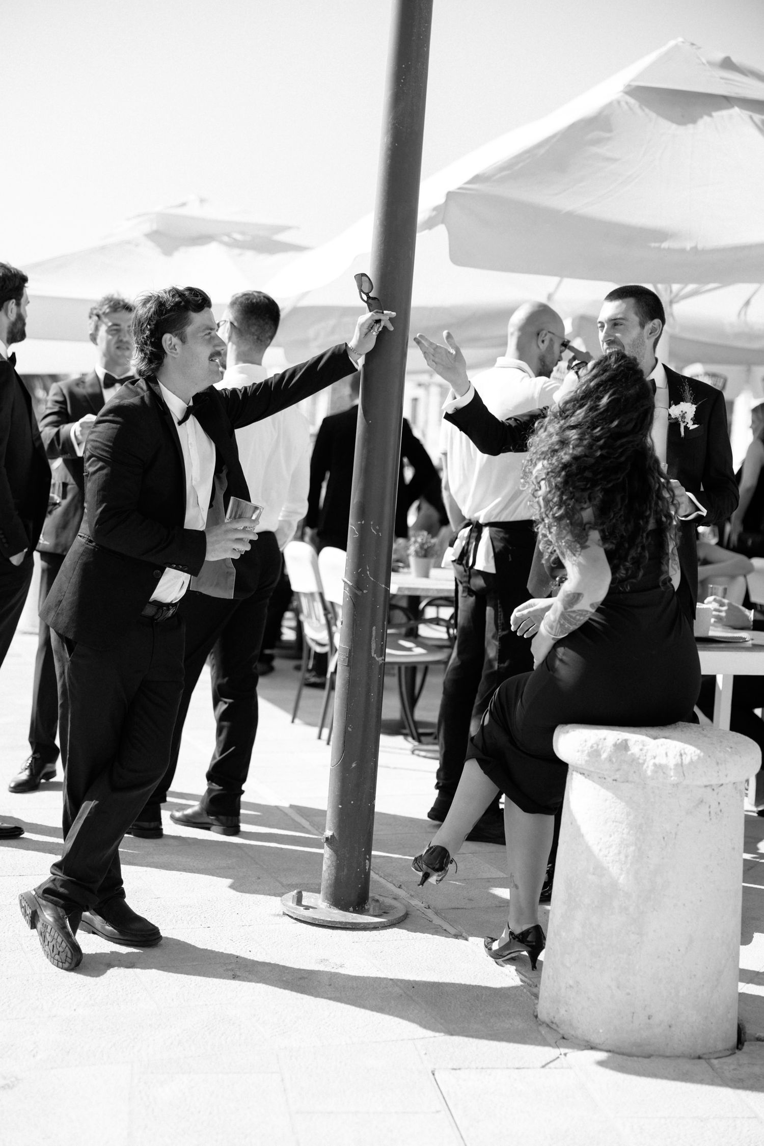 Wedding guests dancing and celebrating around a pole at an outdoor reception.