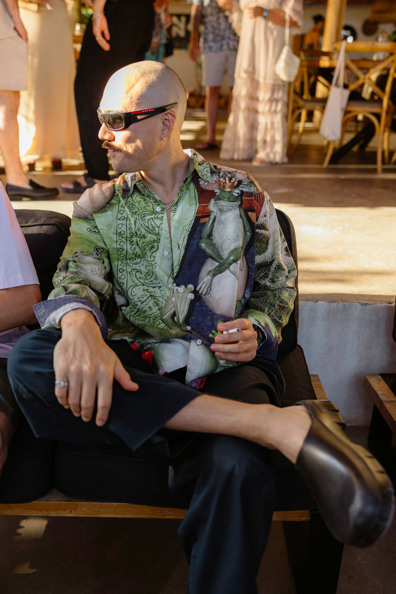 People sitting on outdoor benches wearing casual attire at a social gathering.