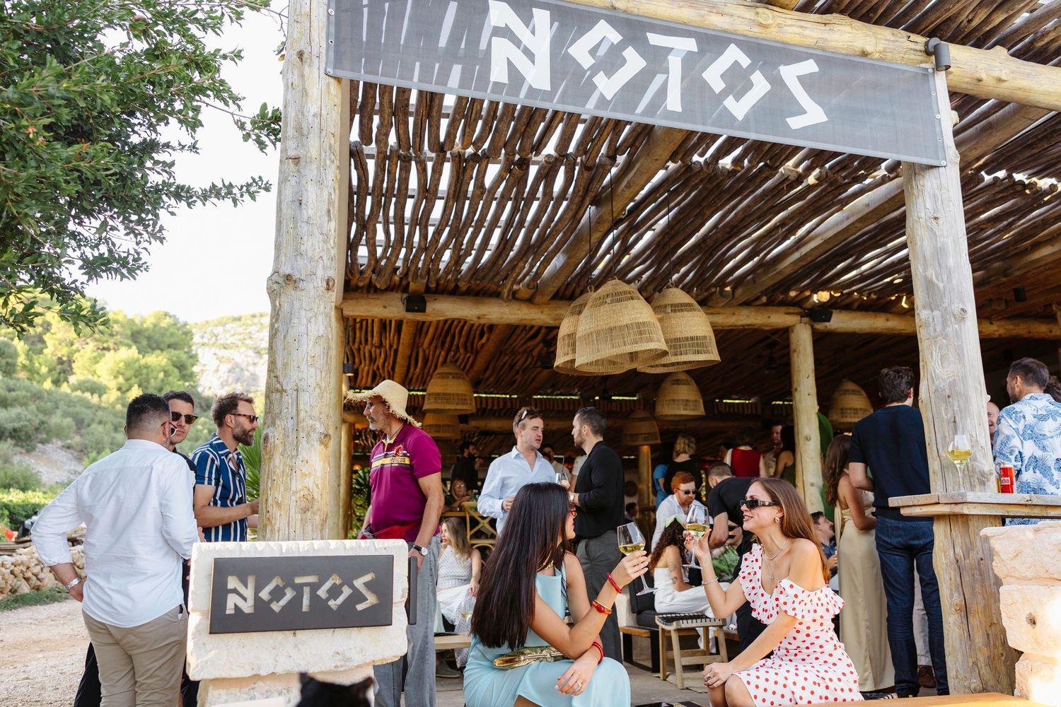 Panoramic view of a covered outdoor venue with guests mingling under a wooden roof.