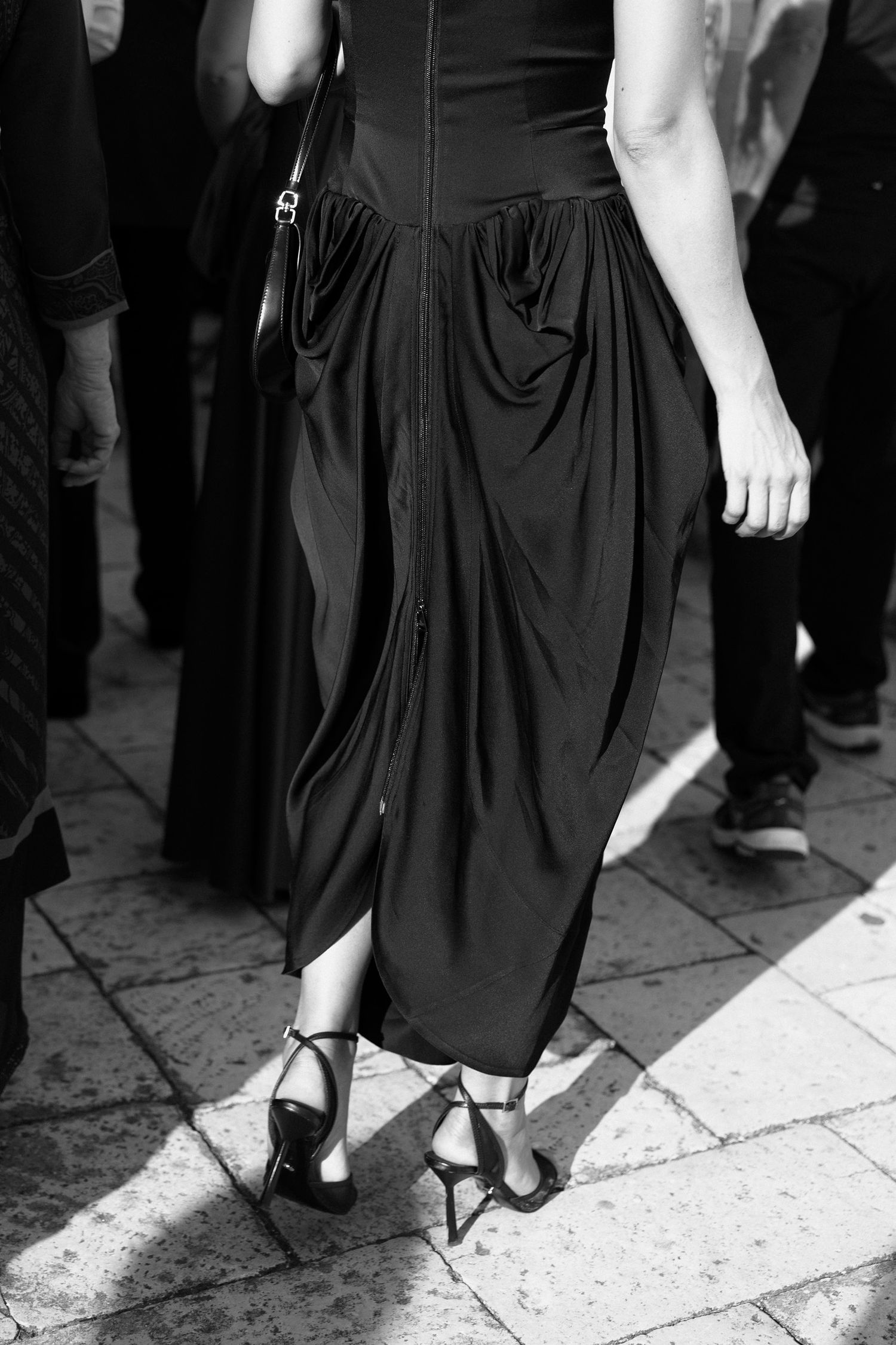 Detail shots of formal black dresses and shoes on stone flooring at elegant event.