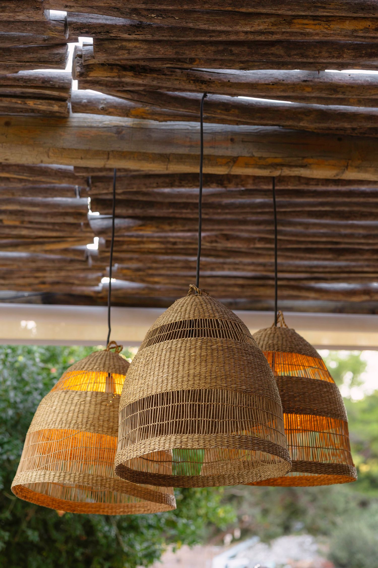 Row of woven basket pendant lights hanging from rustic wooden ceiling.