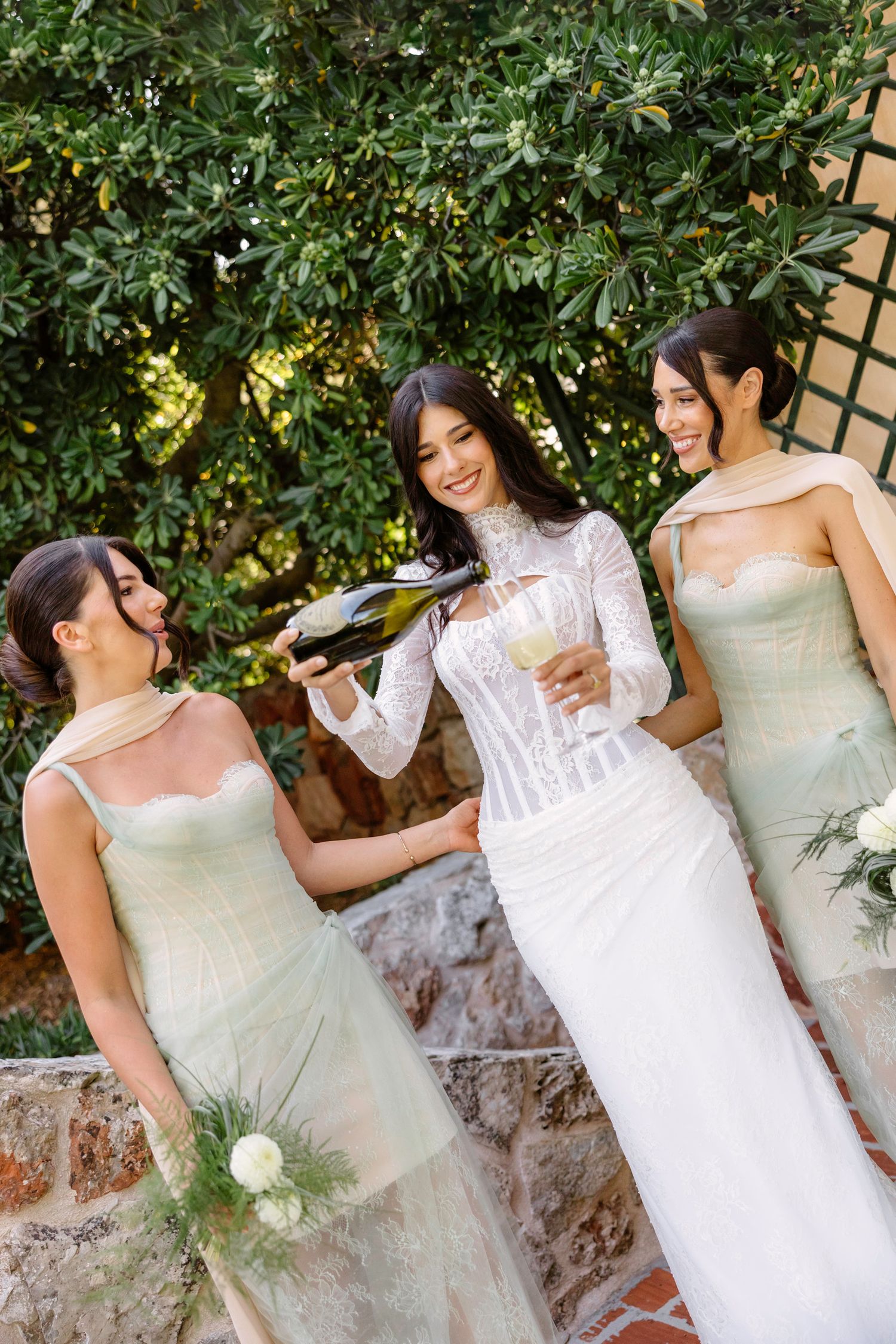 Two people in wedding attire share a joyful moment against a garden backdrop.