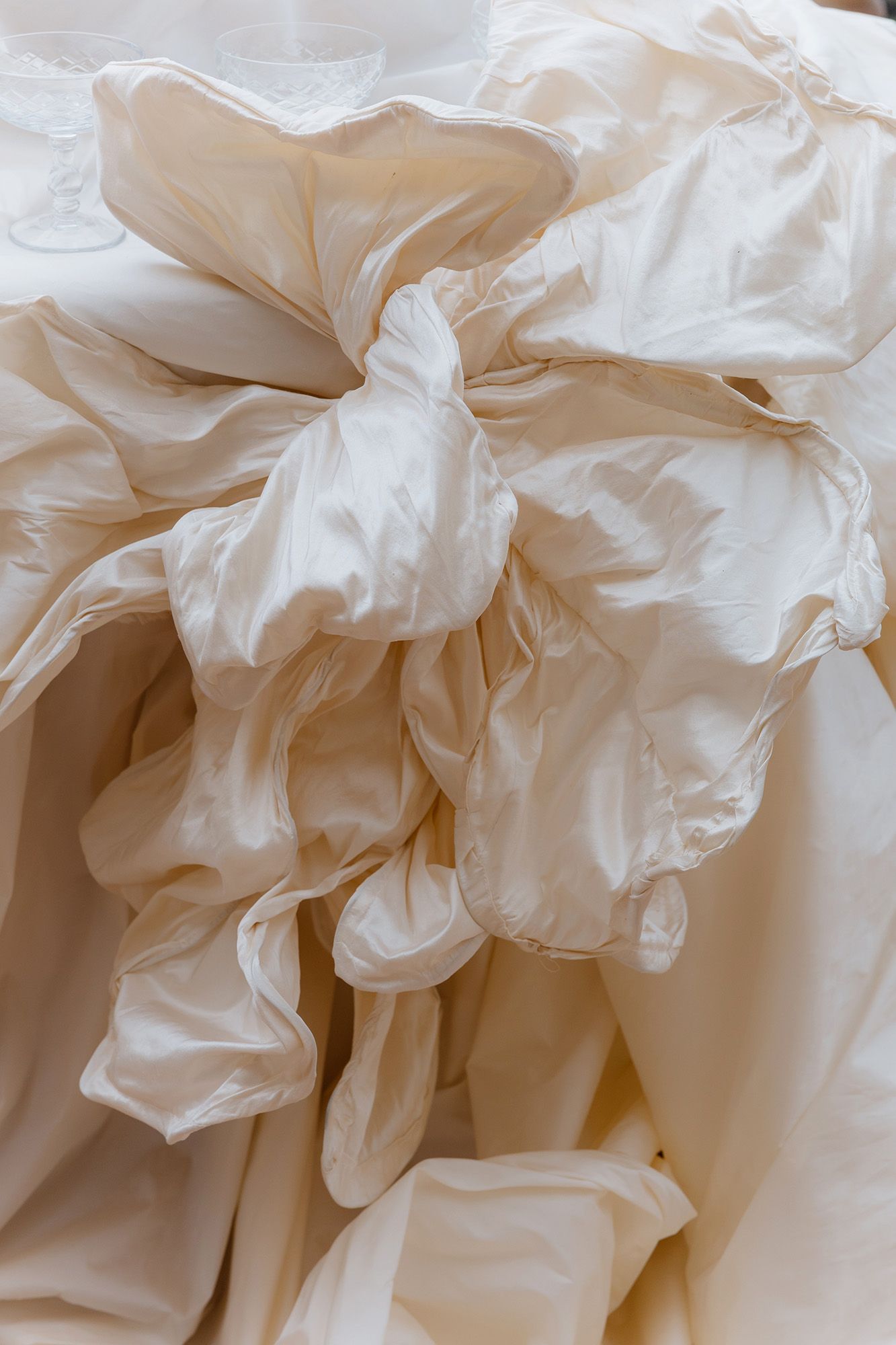 Close-up detail of delicate white fabric ruffles and folds creating an elegant textural pattern.