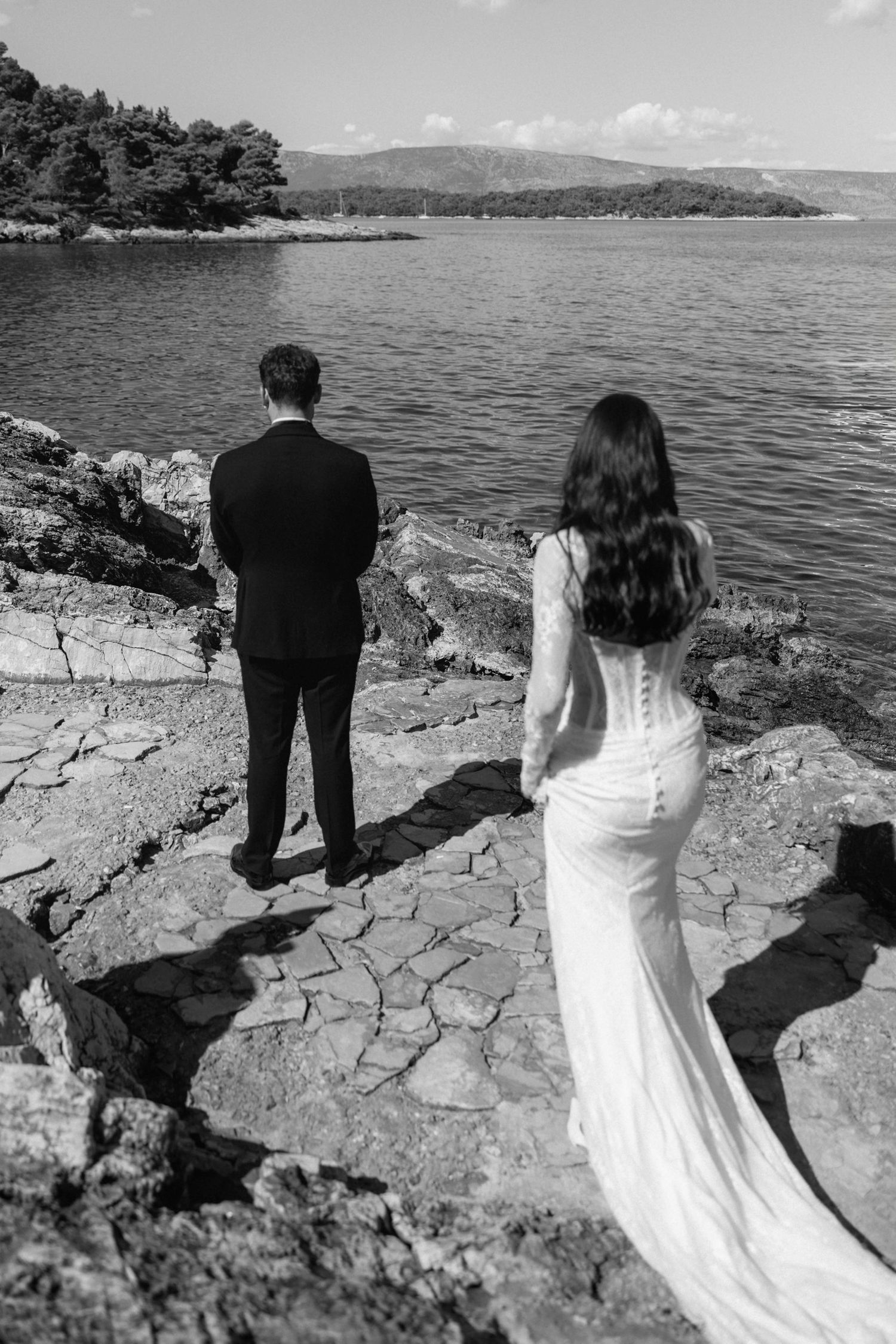 Black and white wedding photo of a couple on rocky coastal cliffs overlooking the ocean.