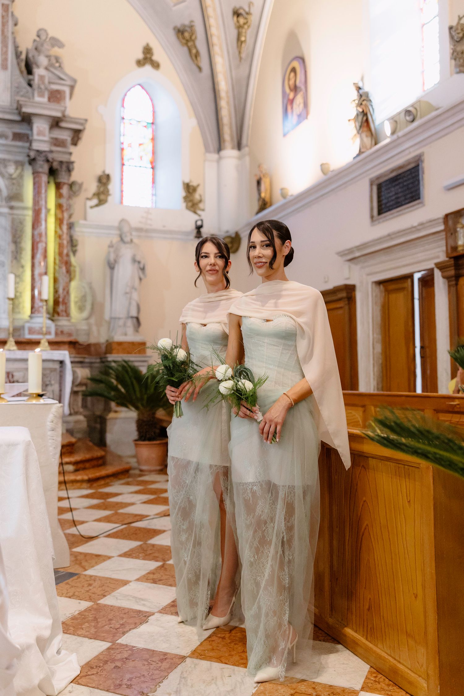 Bridesmaids in sage green dresses standing in a traditional church interior.