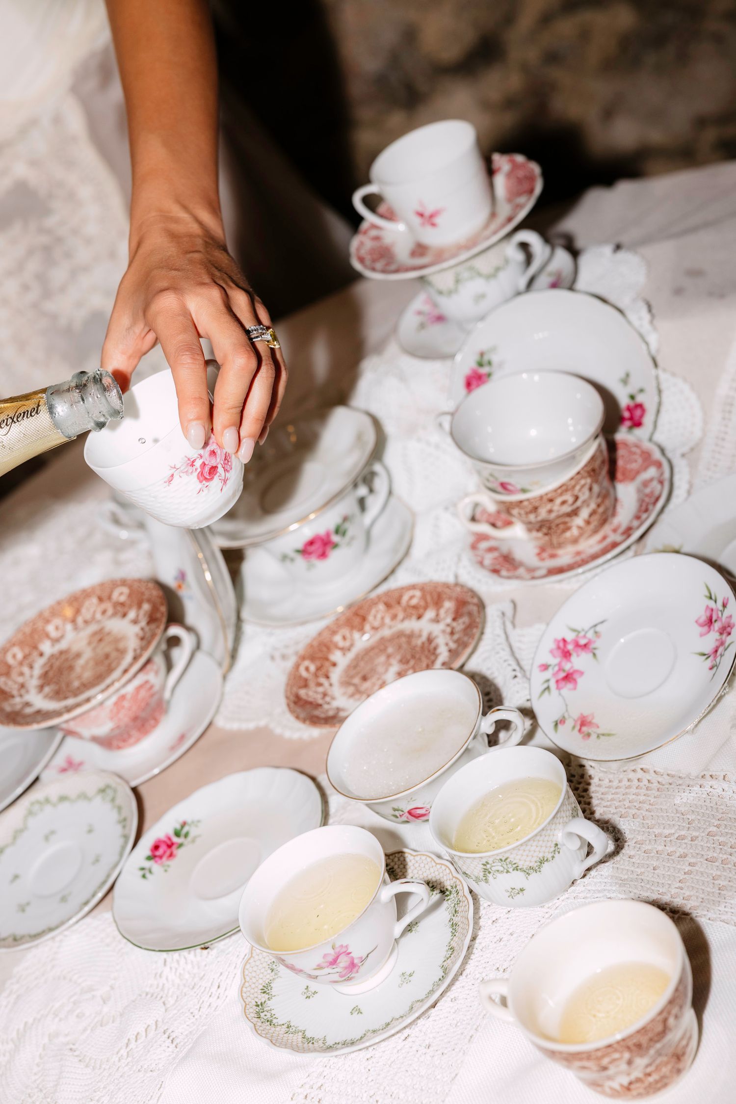 Vintage floral teacups and saucers arranged on white tablecloth at wedding reception. Hvar, Croatia