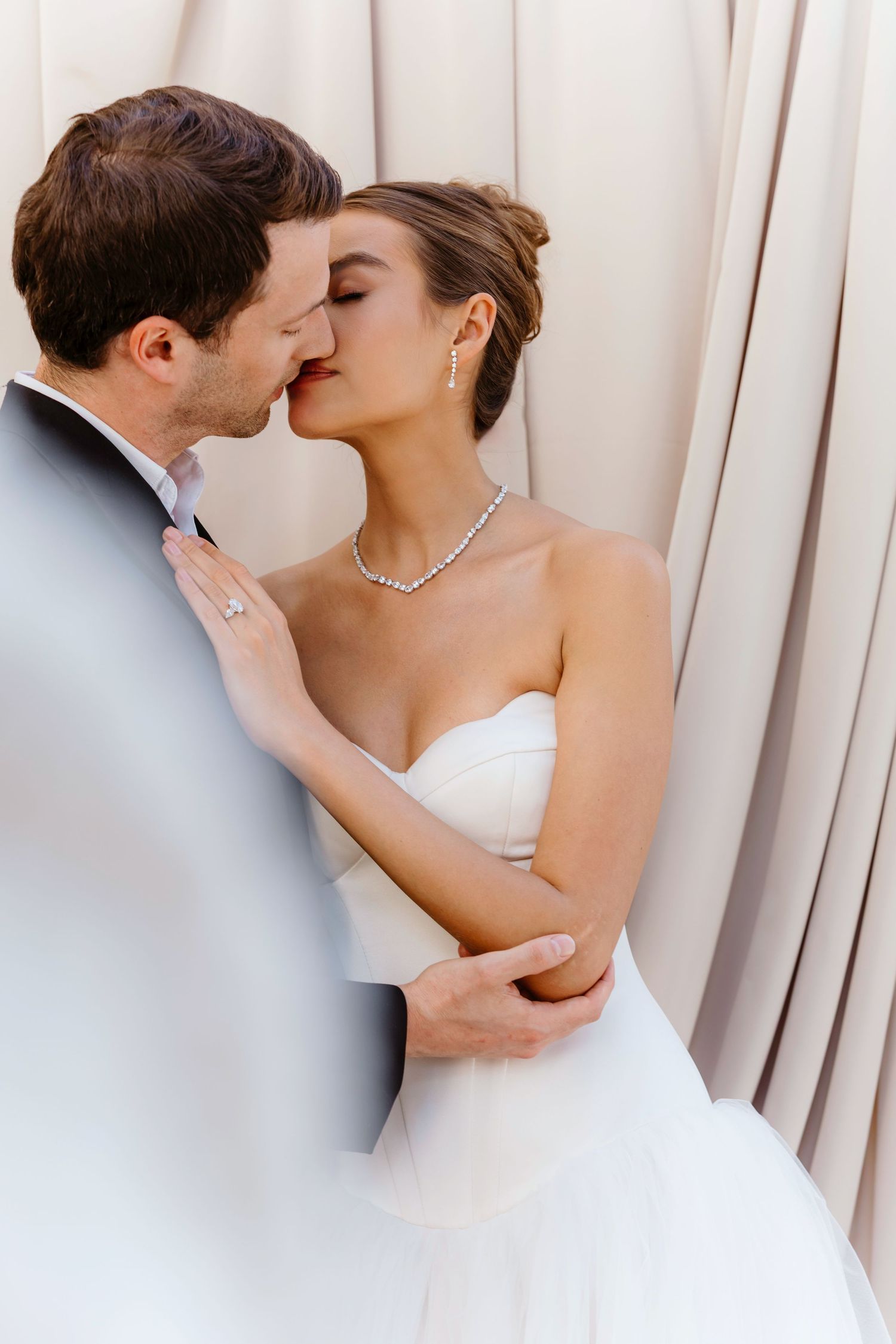 A romantic wedding couple shares three intimate kisses against a light curtained backdrop. Rome, Villa Aurelia