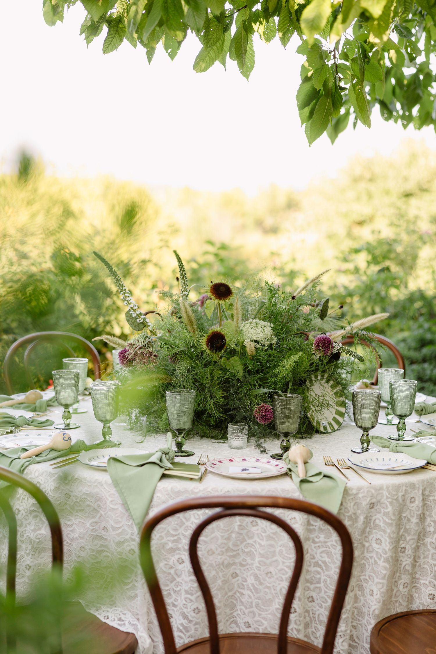 Elegant garden table setting with white linens, floral centerpieces, and vintage glassware. Hvar, Croatia