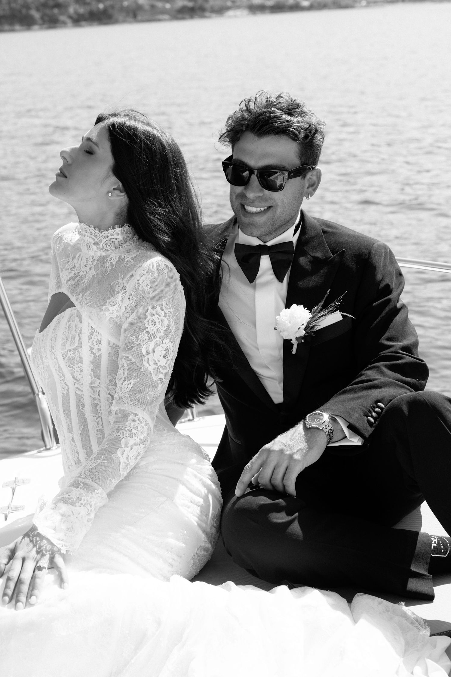 Black and white photo of newlyweds sharing joyful moment on boat.