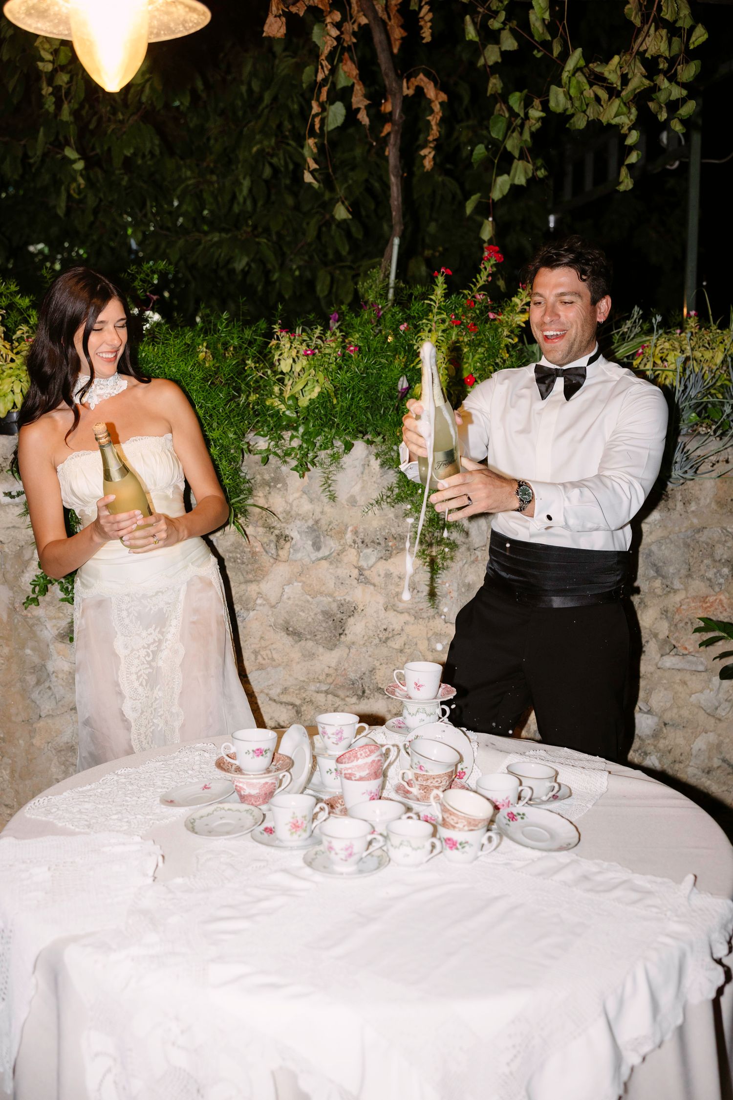 Wedding couple serves drinks at an elegant table setting with white linens. Hvar, Croatia