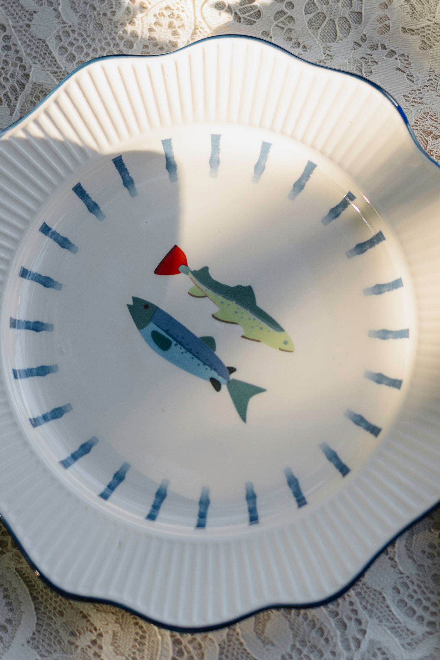 White paper plate decorated with blue and green fish designs in a circular pattern.