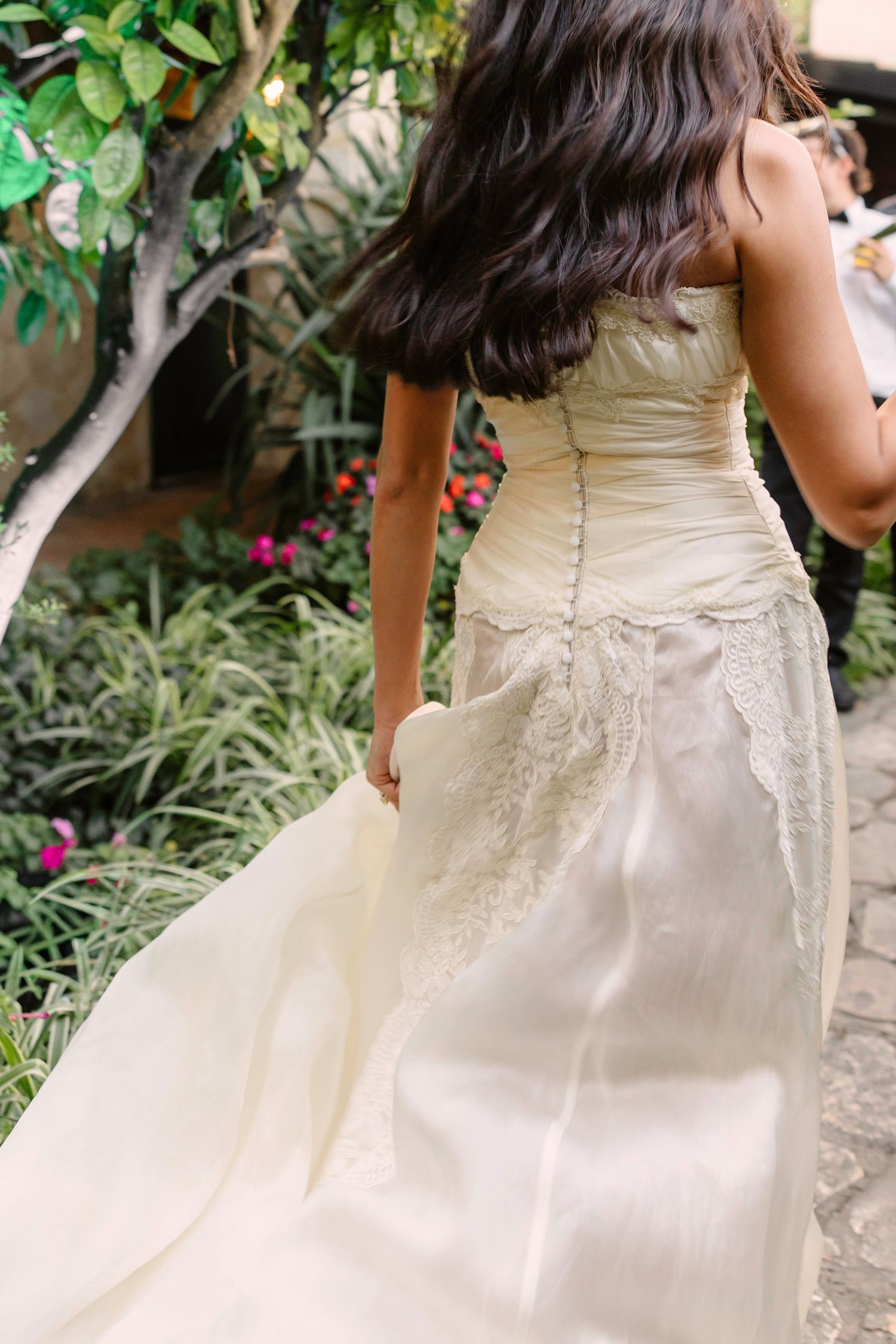 Close-up detail of an ivory wedding dress with intricate lace details in a garden setting. Hvar, Croatia