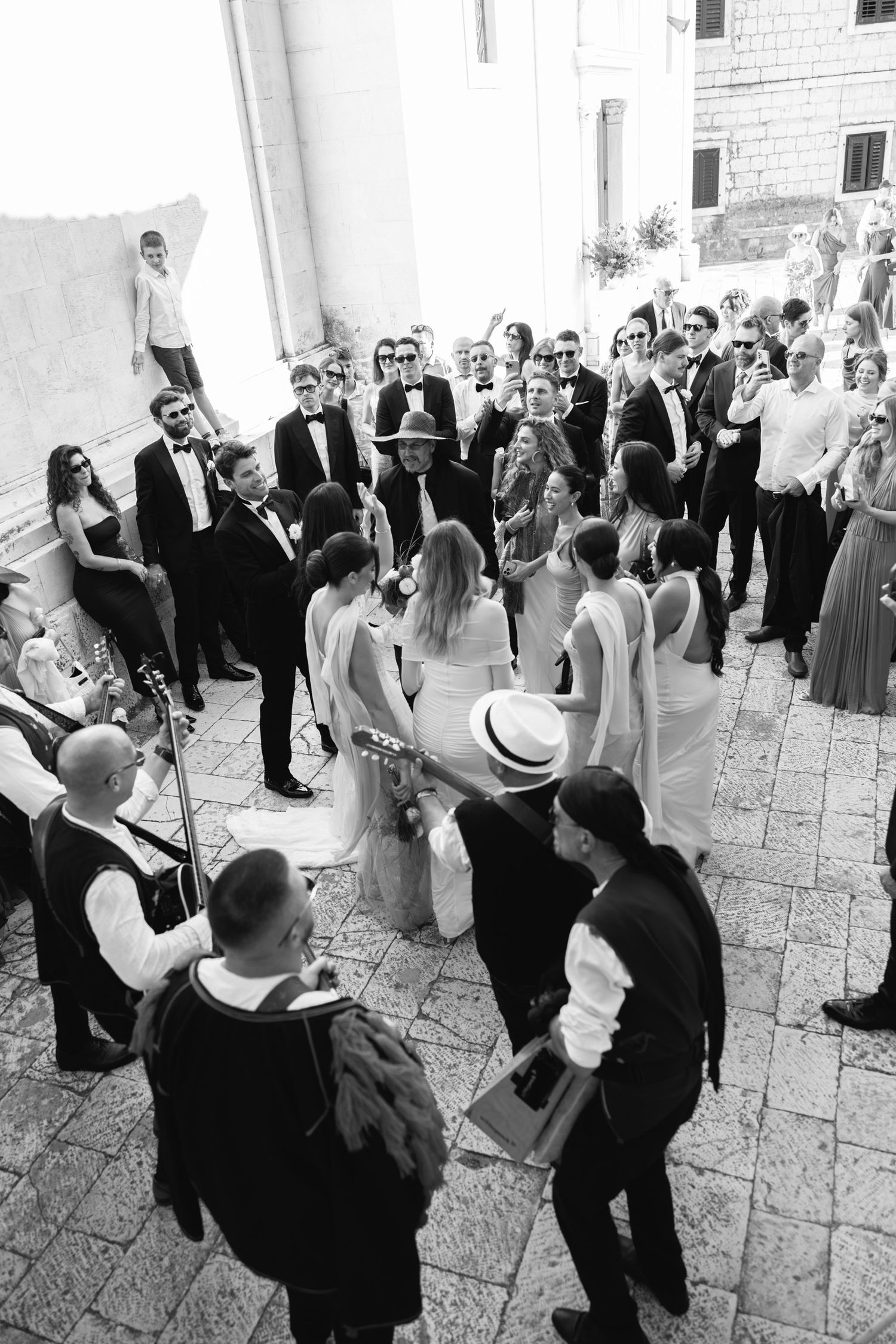 Black and white photos of wedding guests dancing and celebrating on stone patio.
