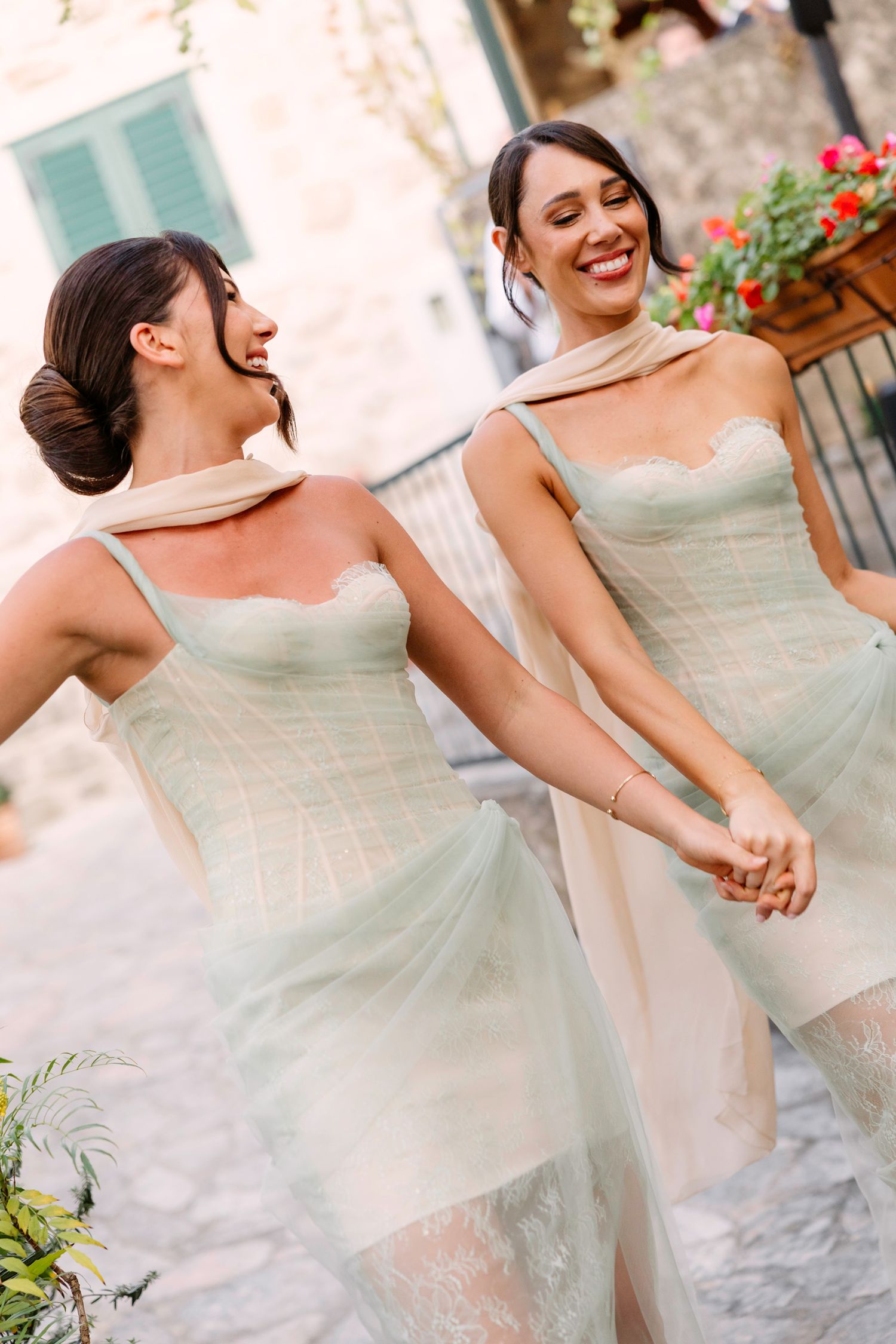 Two bridesmaids in matching mint green dresses share a joyful moment together during a wedding celebration. Hvar, Croatia