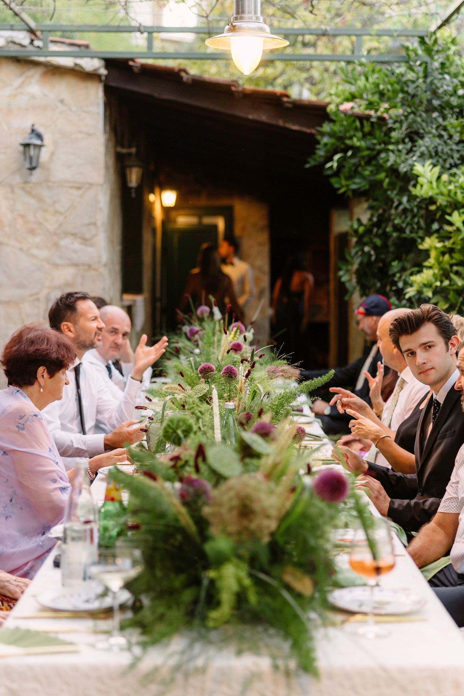 Wedding reception guests seated at outdoor tables with greenery centerpieces. Hvar, Croatia