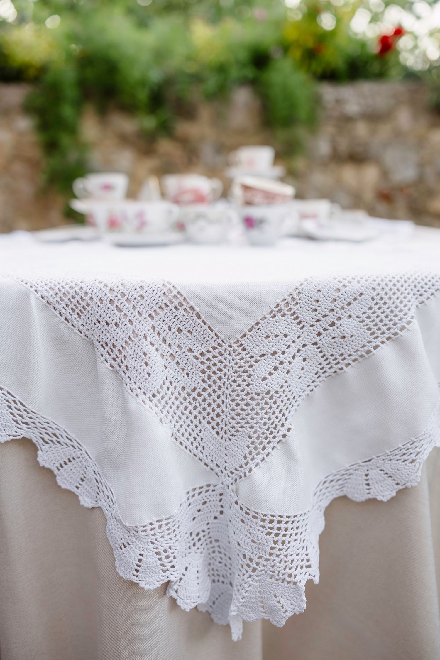 Close-up of intricate white lace tablecloth with scalloped edges against natural light.