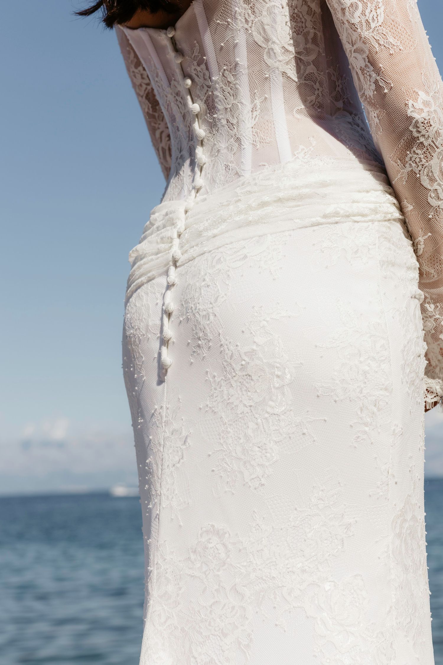 Close-up detail of intricate lace buttons on back of white wedding dress.