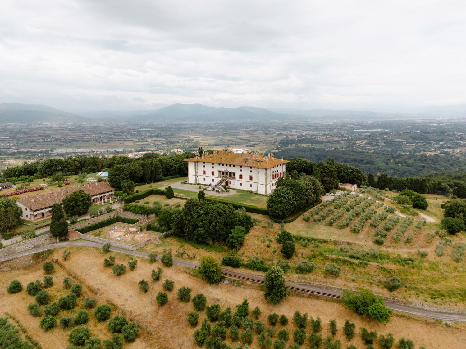 Aerial view of a hilltop villa surrounded by olive groves and rolling hills in the Tuscan countryside. Tuscany, Tenuta di Artimino