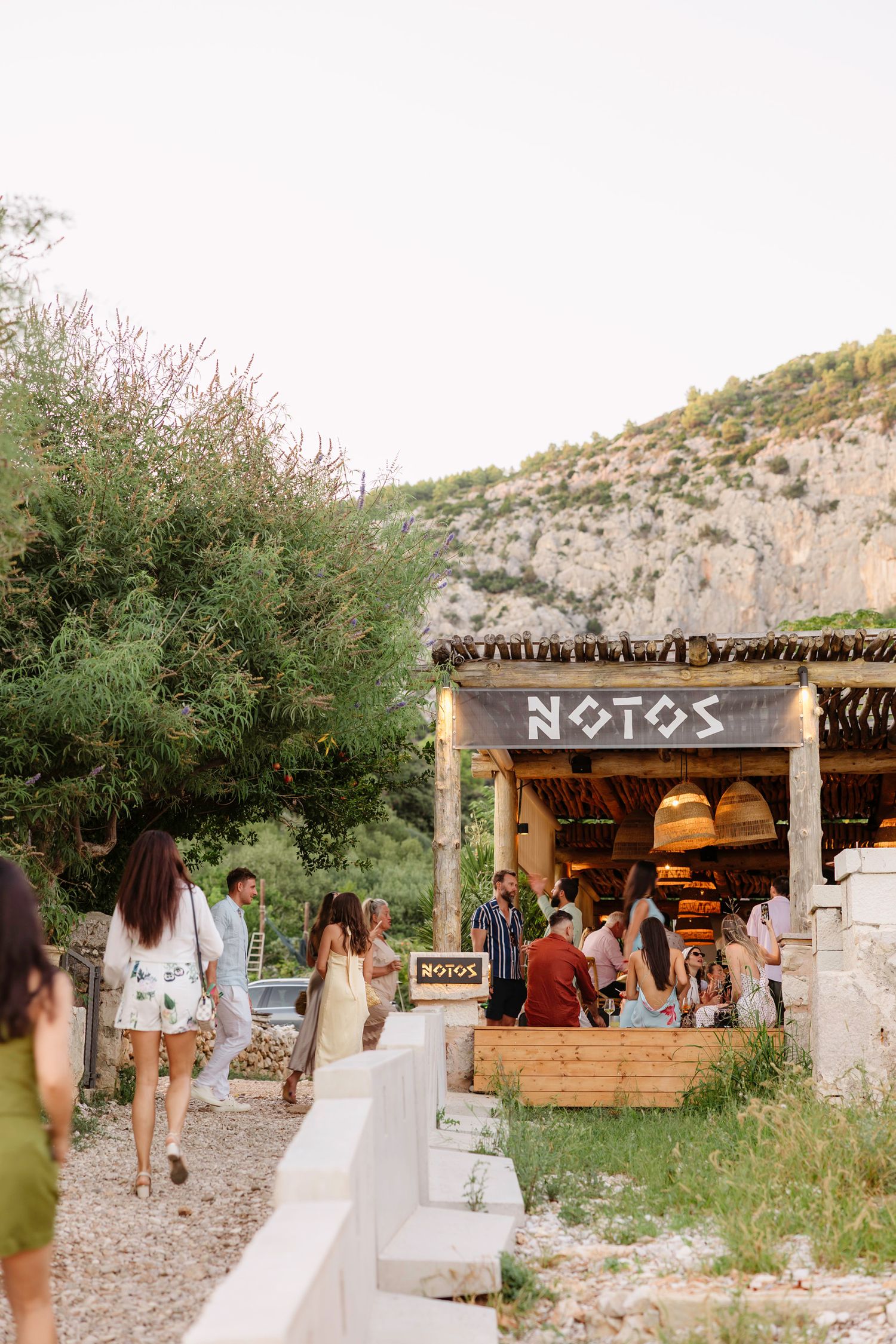 Rustic wooden restaurant entrance with Notos sign along stone pathway.