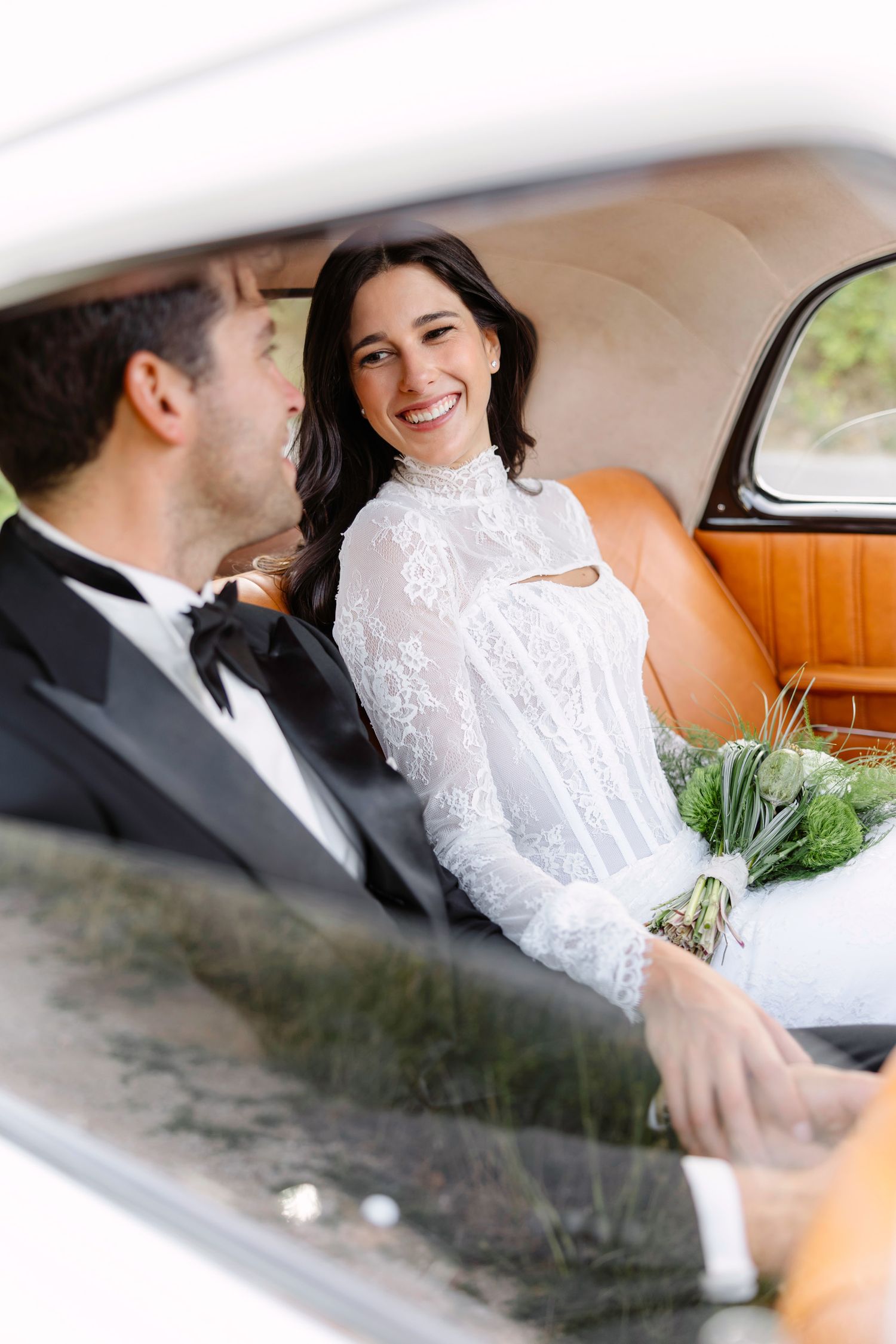 Couple sharing a joyful moment in vintage car with white leather interior. Hvar, Croatia