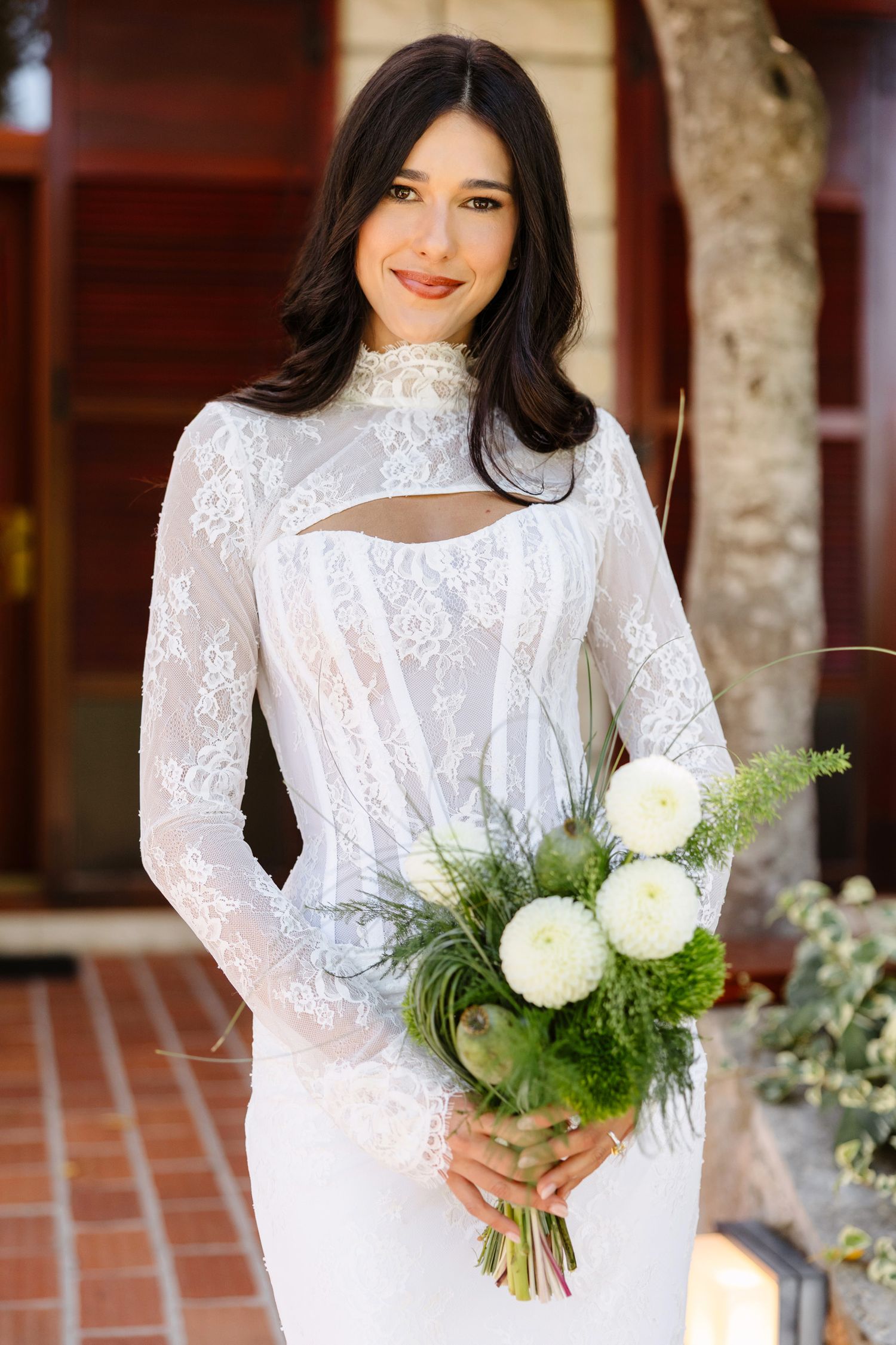 Elegant bridal portrait featuring a white lace gown and bouquet of white flowers.