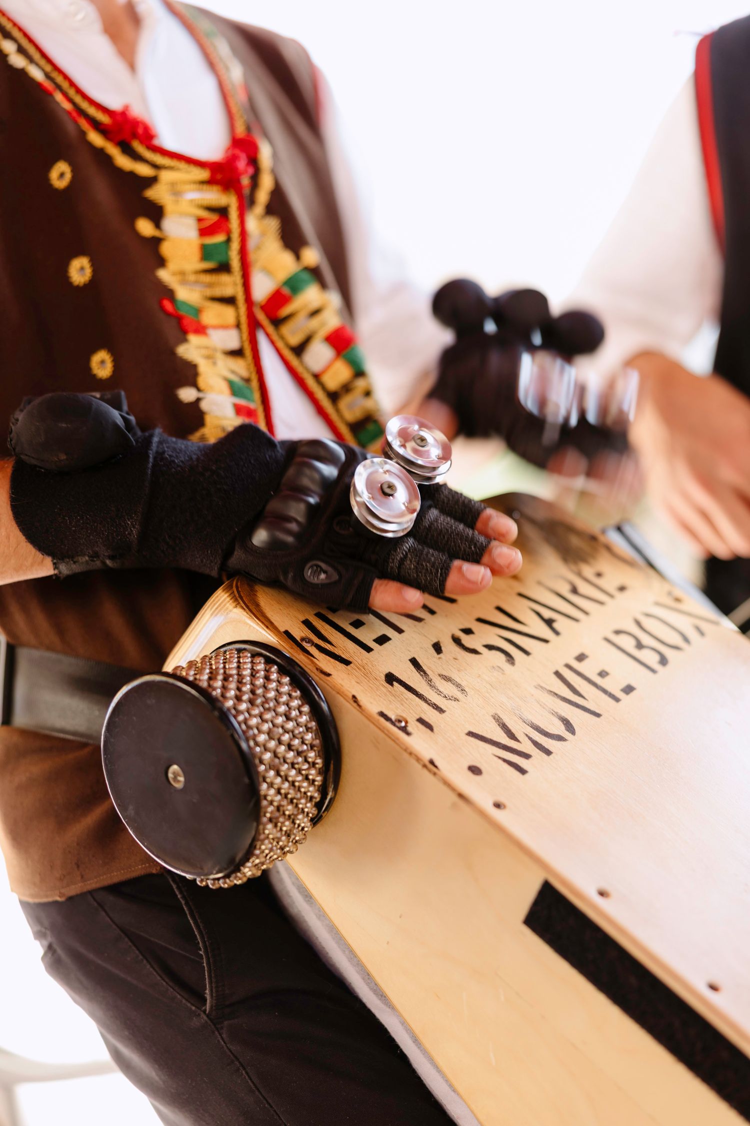 Close-up of traditional musician's hands holding percussion instruments over a wooden surface.