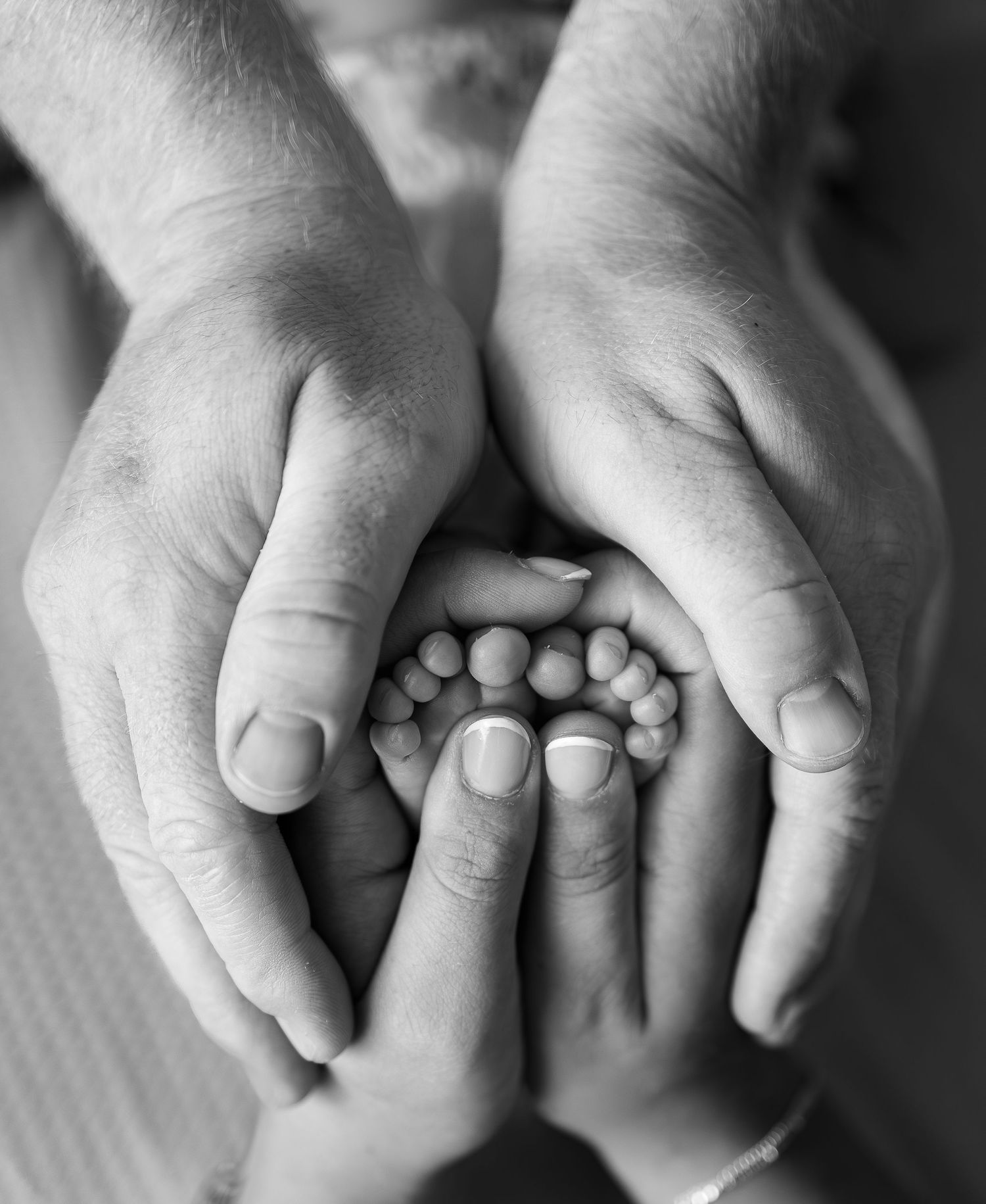 Close up of mum and dads hands cupping newborn babies feet during a at home Newborn Photoshoot in Pocklington.