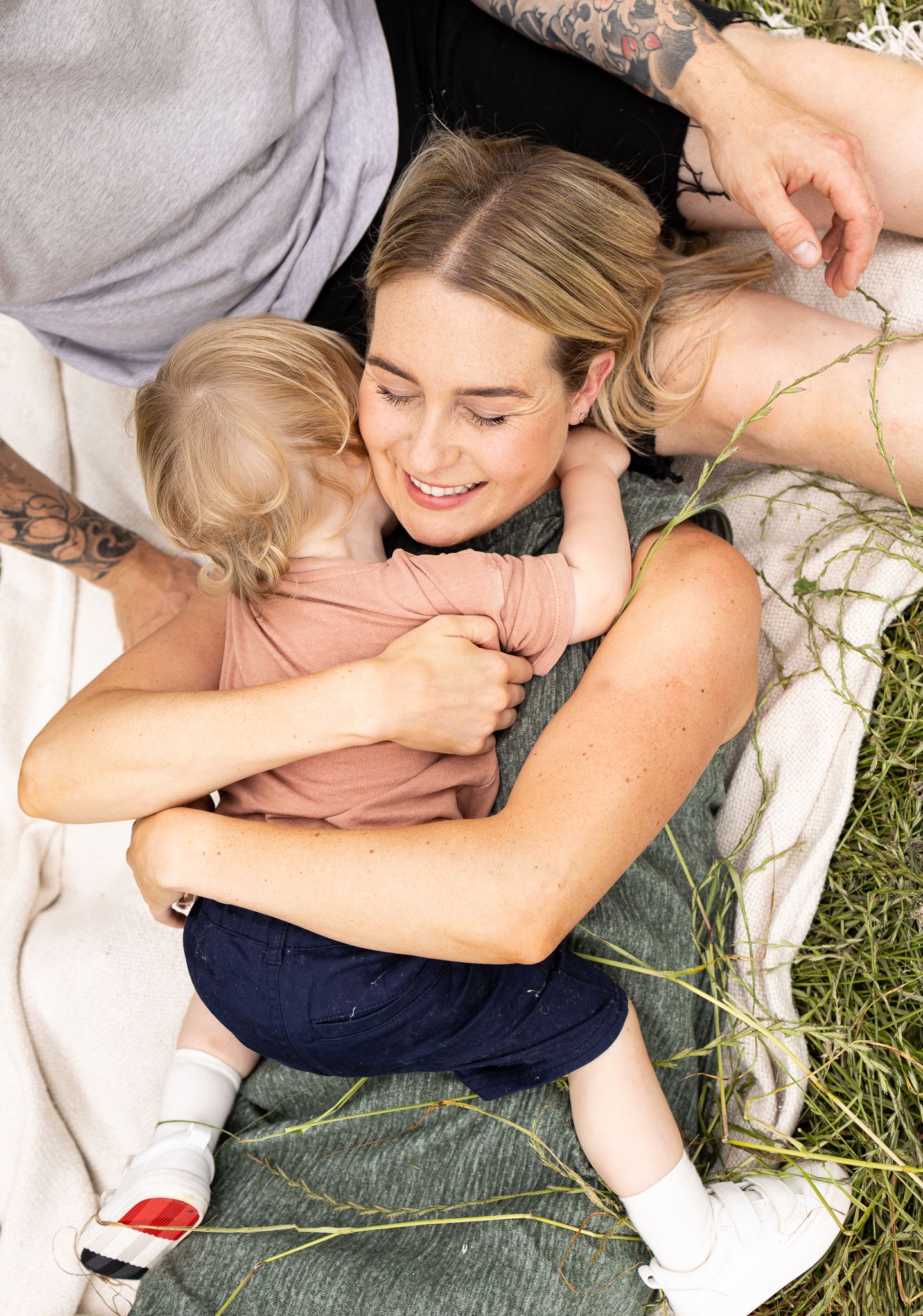 Sweet candid moment of embrace on blanket in grassy field.