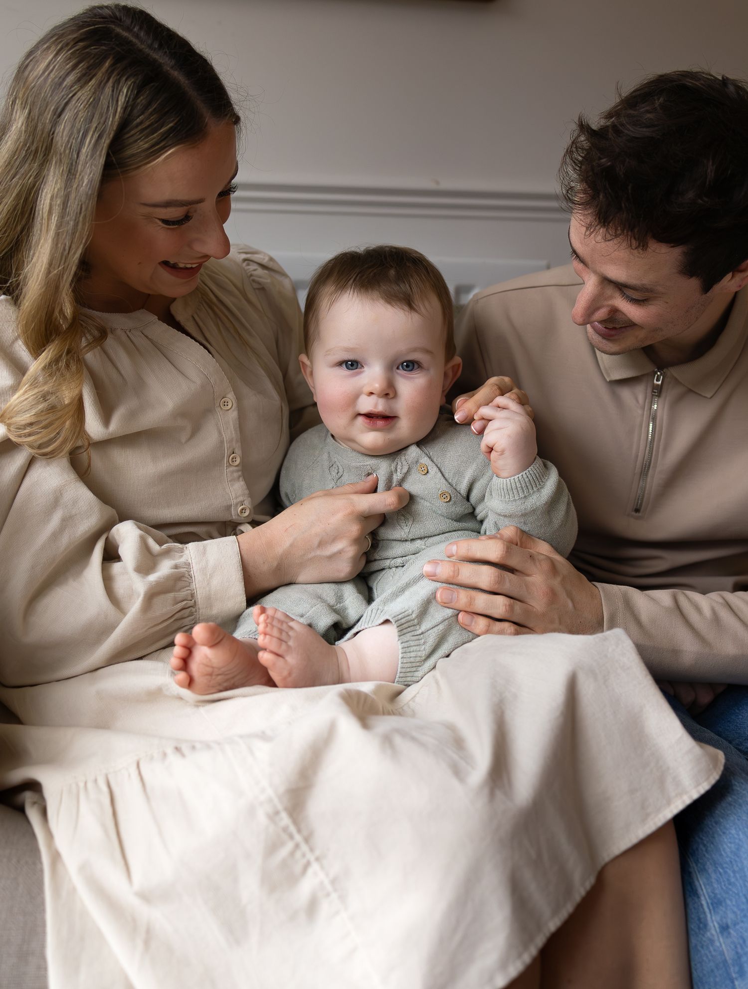 Baby boy with big eyes having a cuddle with his mum and dad during family photoshoot in Stamford Bridge
