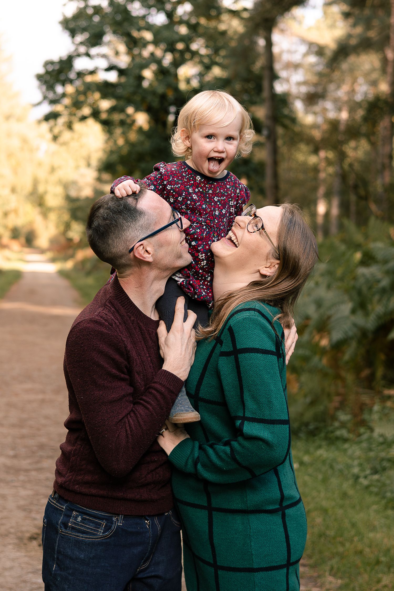 Joyful family moment outdoors on autumn path with trees.
