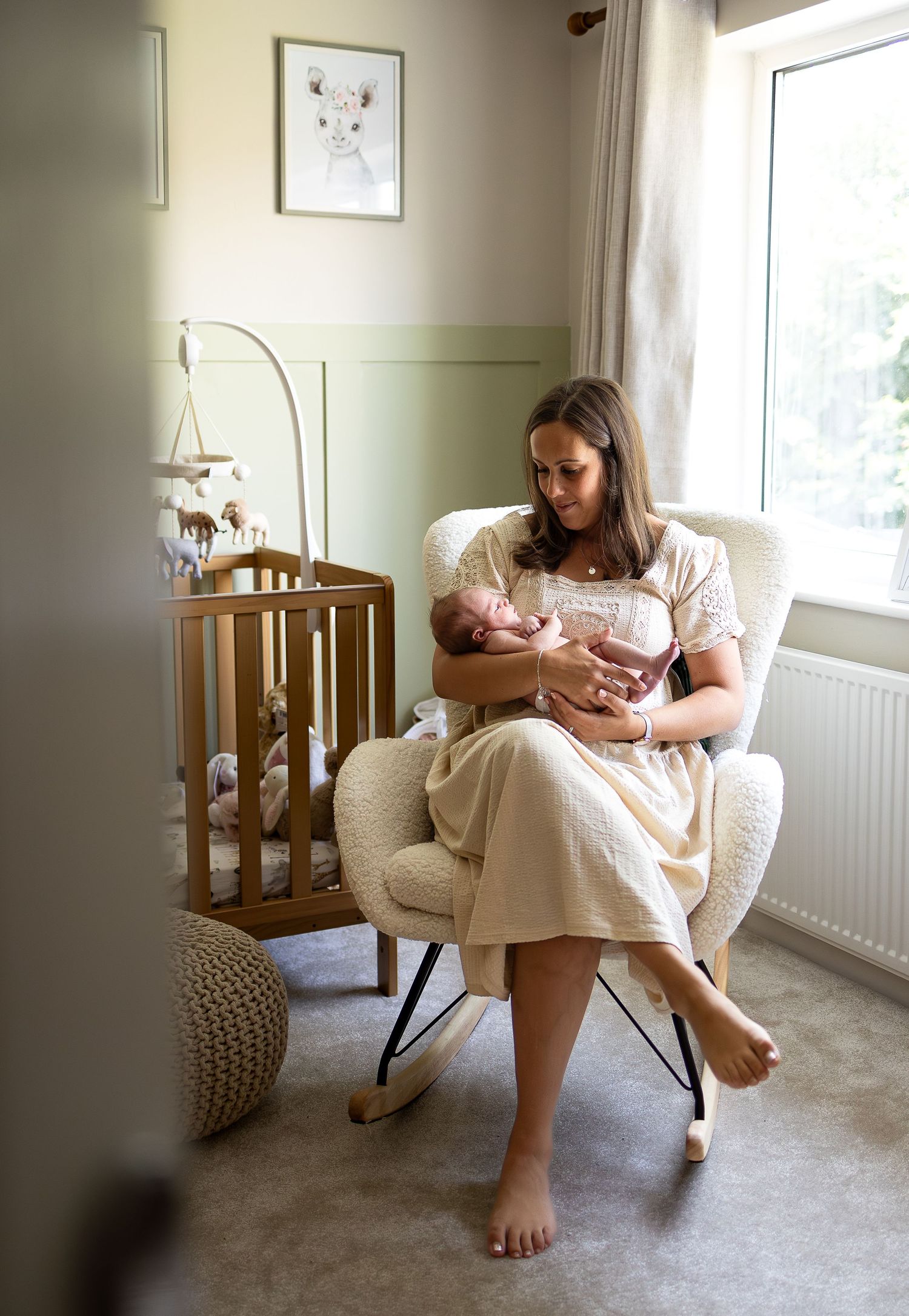 Mum cuddles baby in nursery during newborn photoshoot at home in York.
