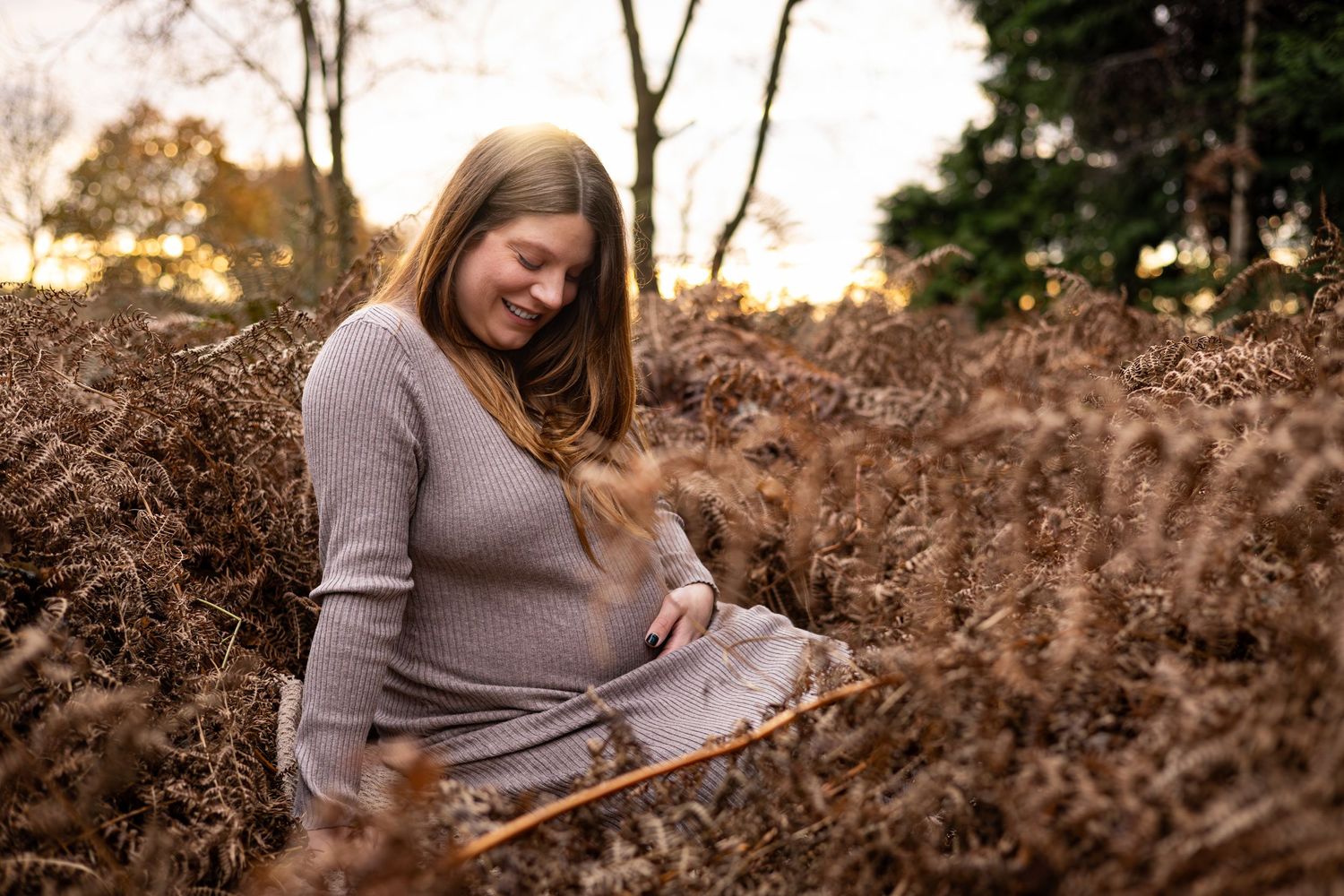 Mummy to be cradles her bump in a Golden Hour Maternity Photoshoot in a gorgeous bracken filled wooden near York.