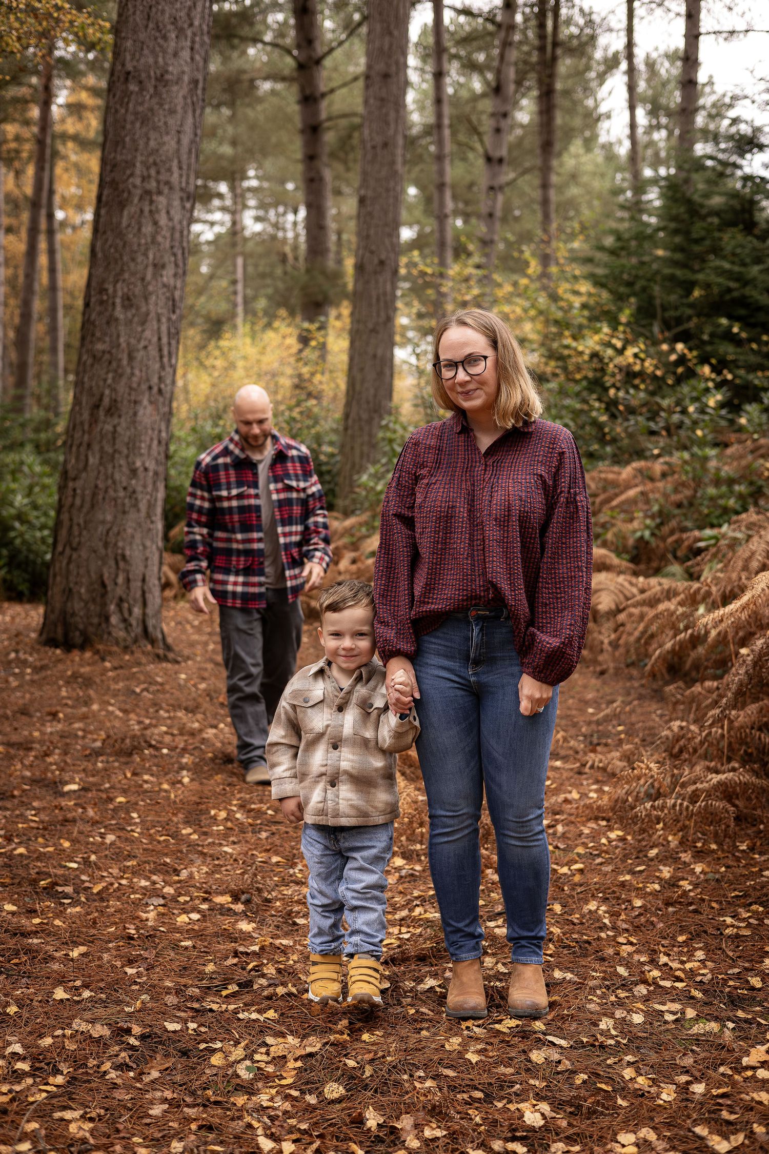 A casual family walk along a forest path covered in fallen pine needles.