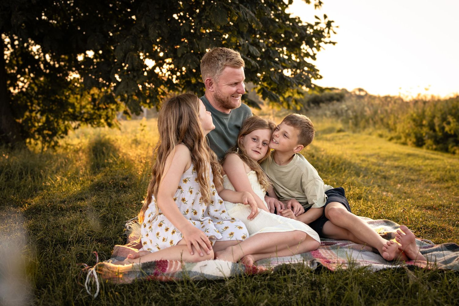 Family enjoying quality time together during sunset photoshoot in grassy field.
