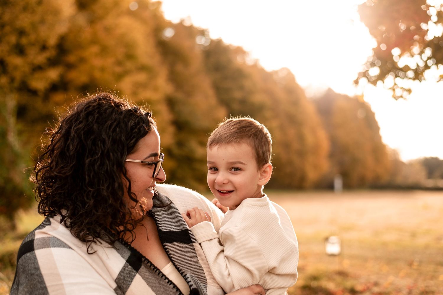 Family shares tender moments together during golden hour photoshoot in autumn park setting.