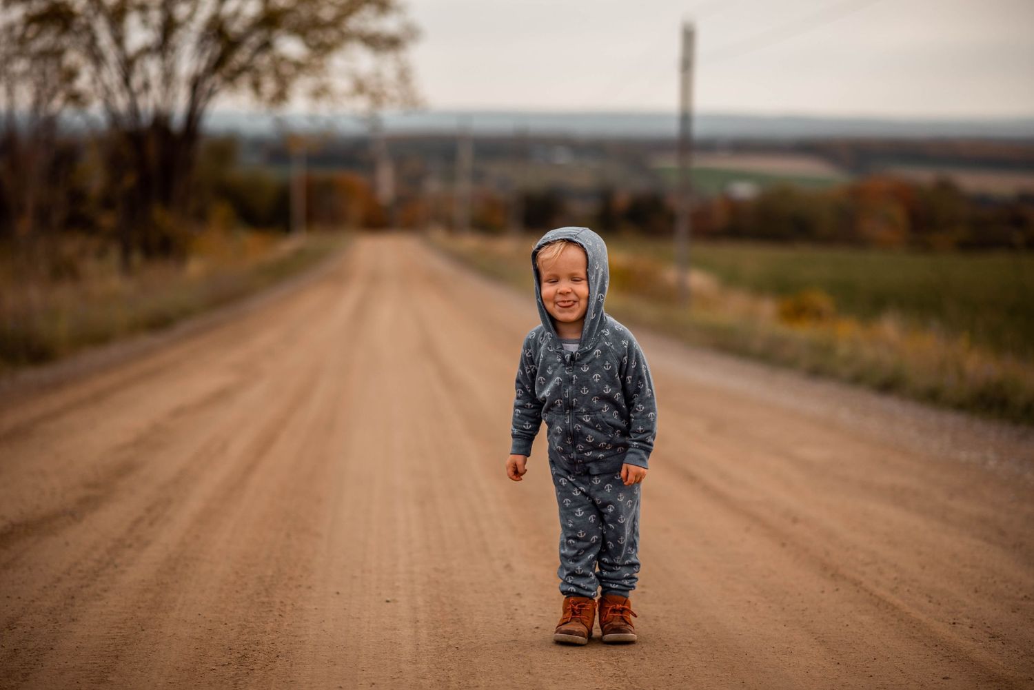 Array of seven sequential images showing a toddler walking along a gravel country road on an autumn day.