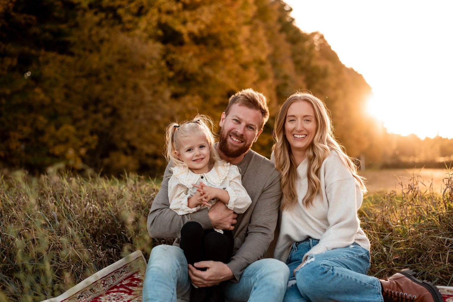 A candid family portrait at sunset in a natural outdoor setting.