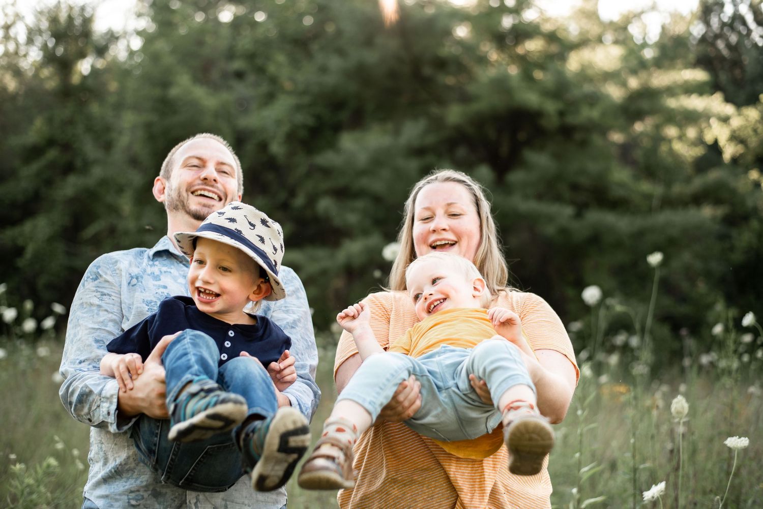Family sharing laughter and joy together in a sunlit meadow at dusk.