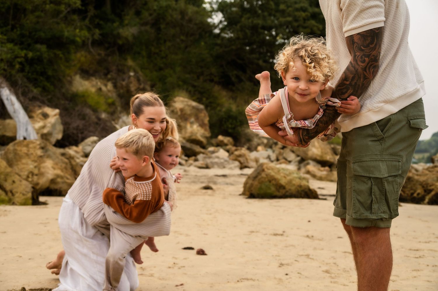 A happy family having fun together on a sunny beach with heather-covered cliffs in the background.