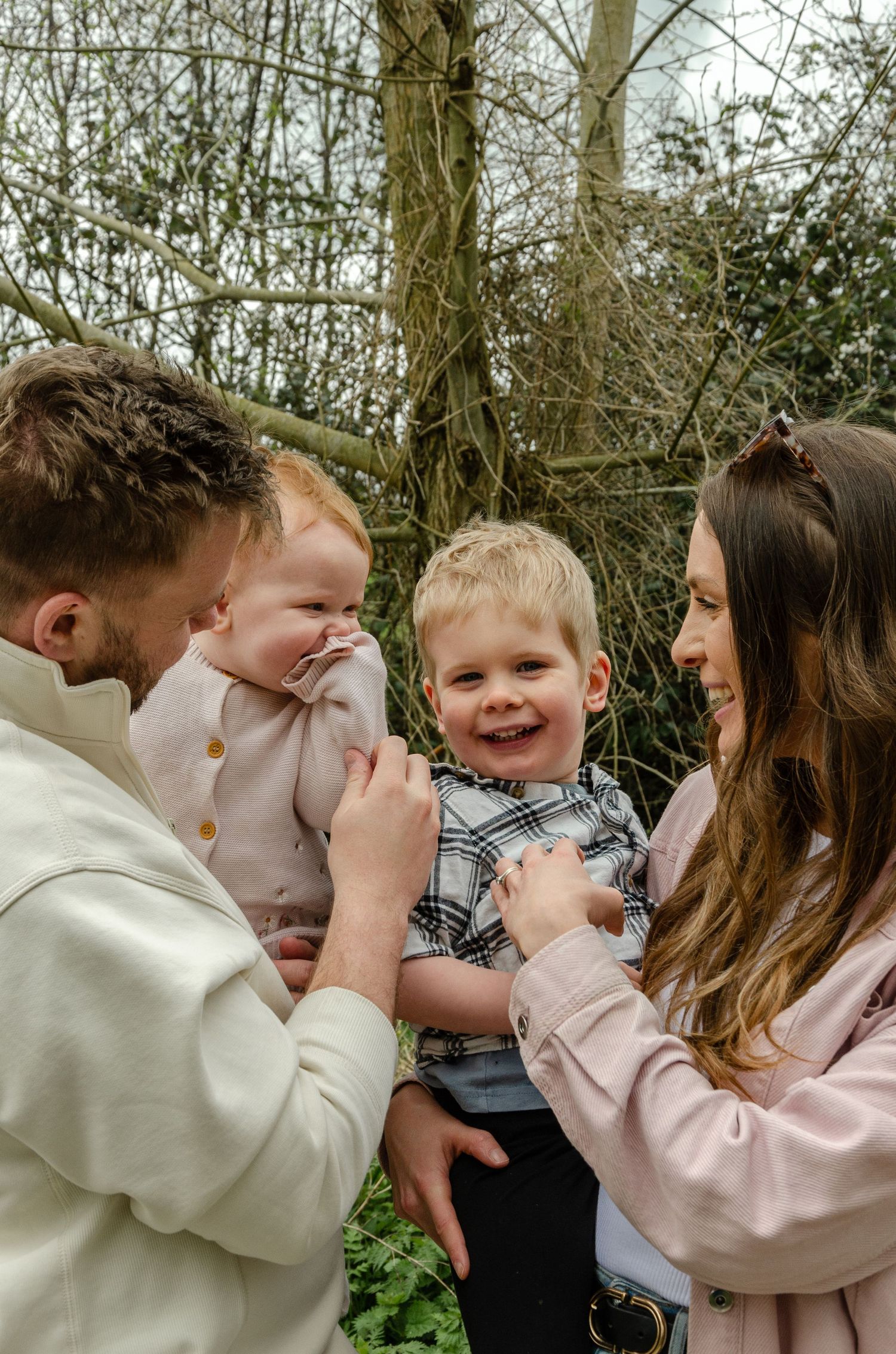 Family sharing playful moments together in a wooded setting.