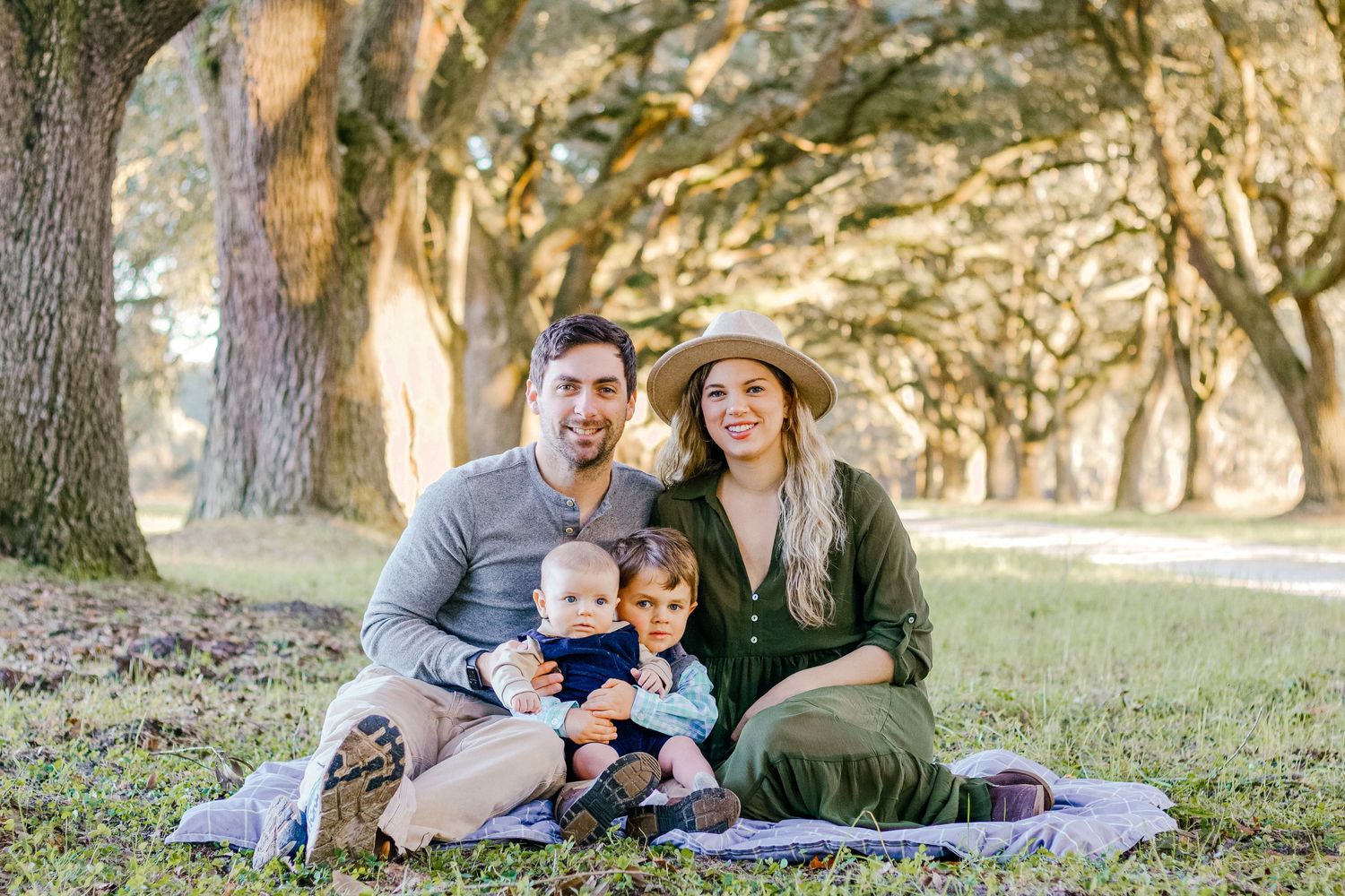 Family enjoying a picnic under moss-draped oak trees on a sunny afternoon.