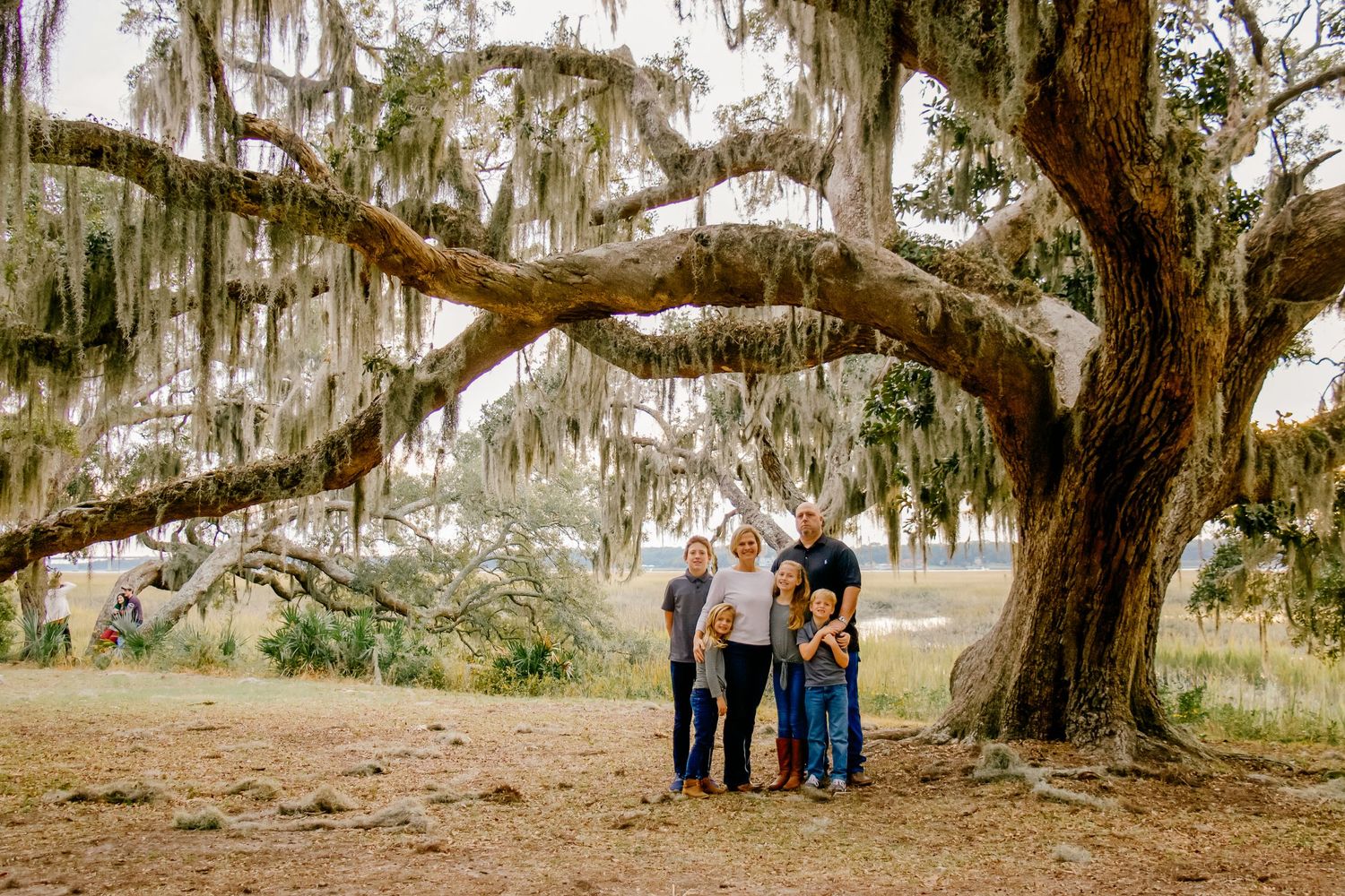 Family photo session under massive oak tree with Spanish moss in natural setting.
