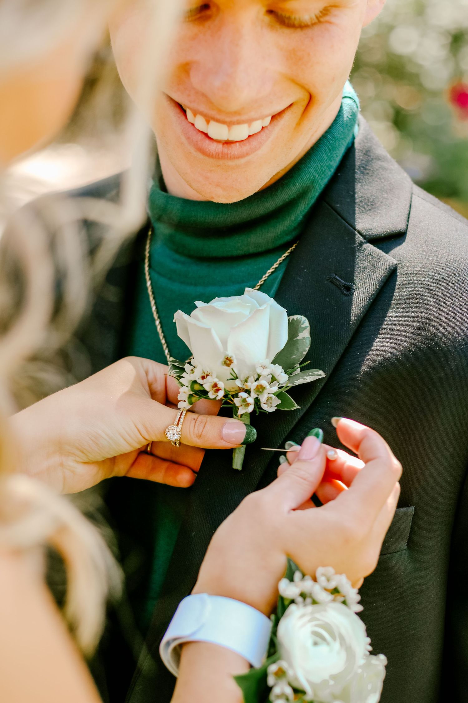 White rose and baby's breath boutonniere being attached to formal attire.