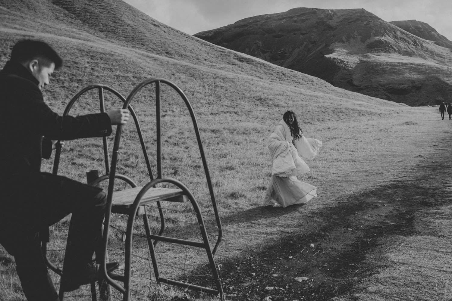 A dreamy black and white scene of figures near playground swings on a misty hillside.