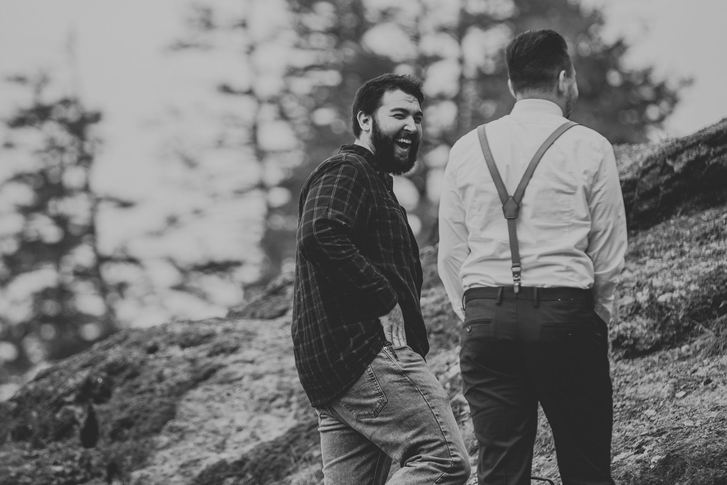 Candid moment between wedding party members on mountainside during ceremony.