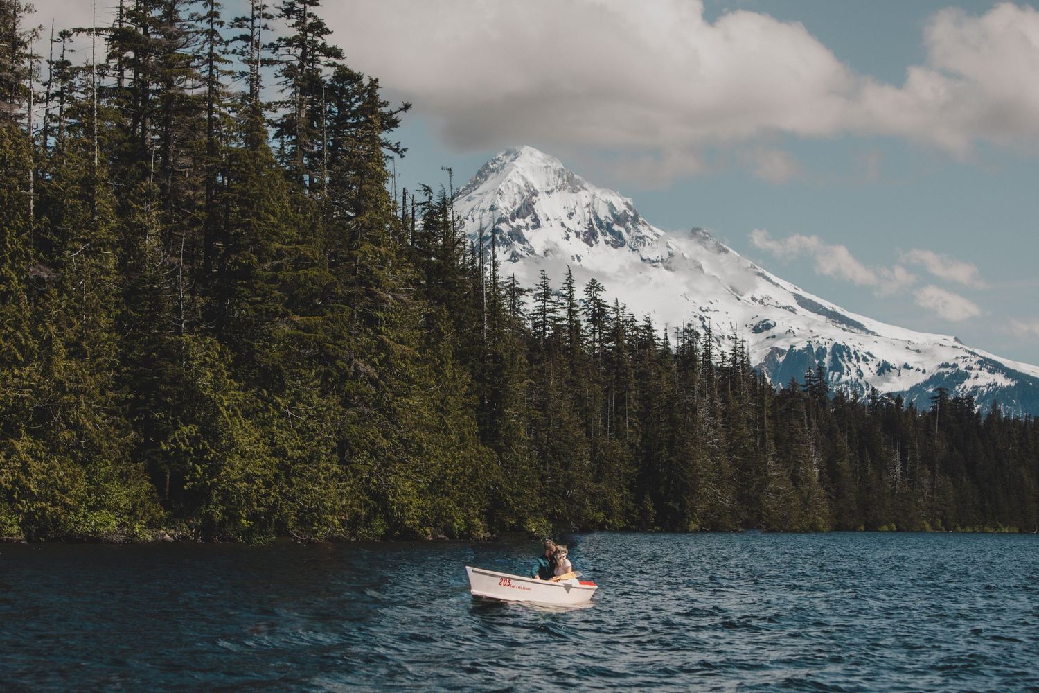 Small white boat on lake with snow-capped Mt Hood in background.