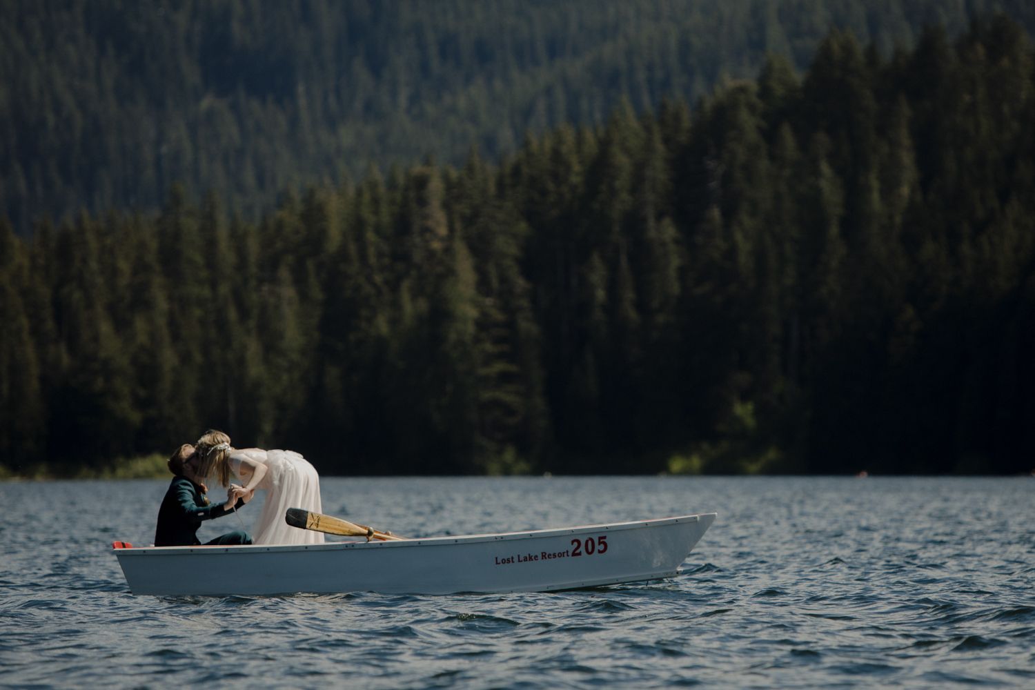A romantic moment captured in a rowboat on a serene mountain lake.