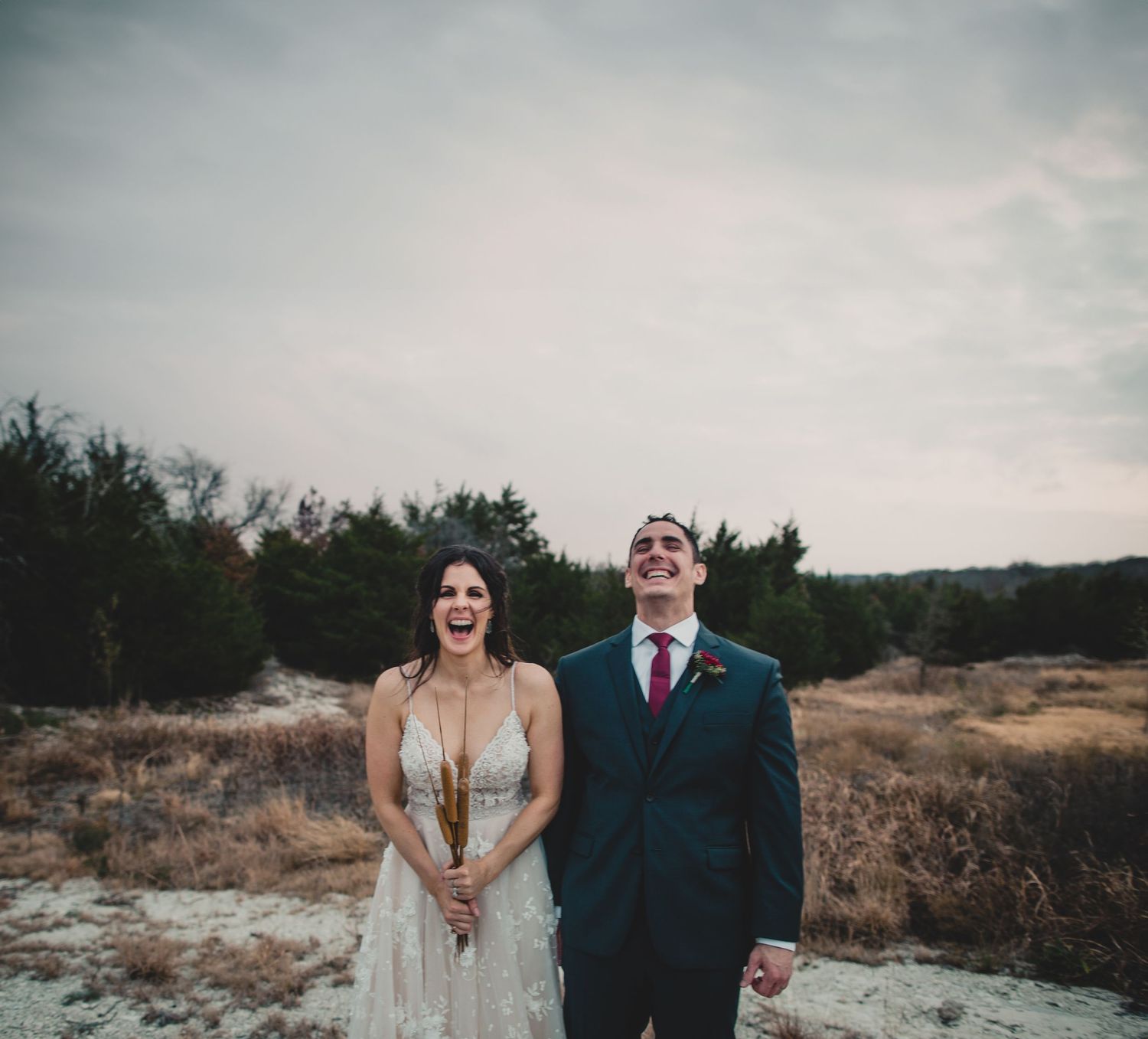 Artistic wedding portrait with couple against moody winter backdrop.
