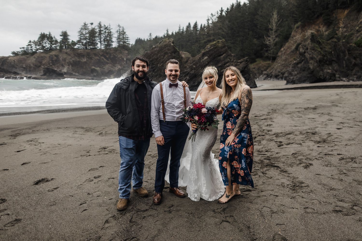 A group portrait on a moody Pacific Northwest beach with dramatic cliffs and crashing waves.