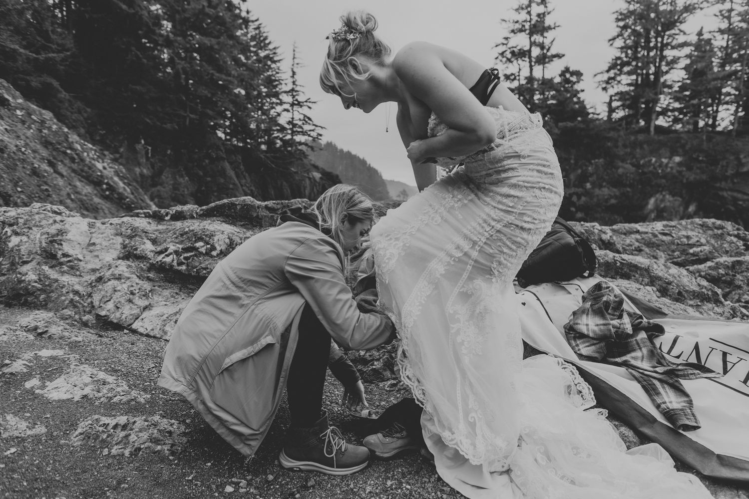 Wedding couple preparing on rocky coastal cliffs during an intimate outdoor ceremony.